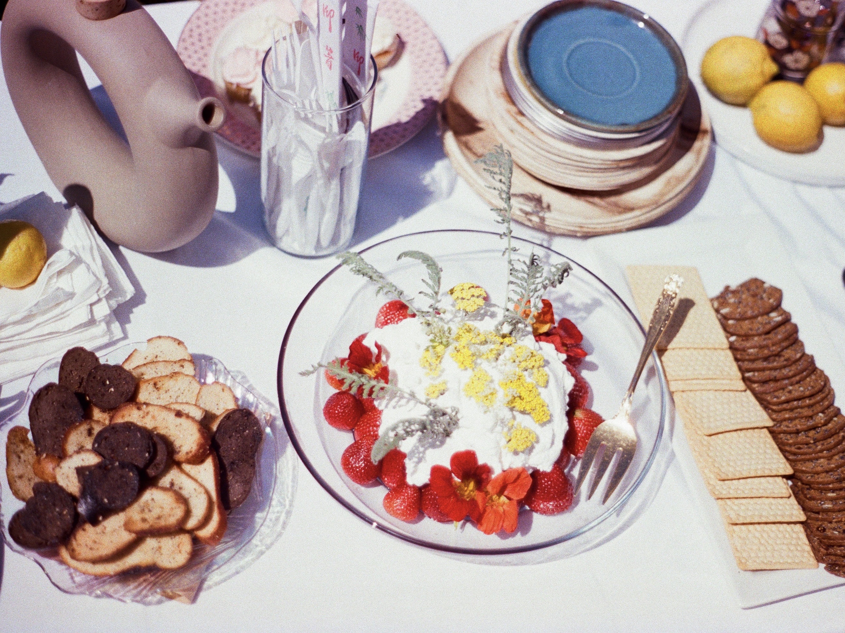 image of a tablescape featuring bright white and red tones from strawberries and cream, a selection of crackers and stoneware