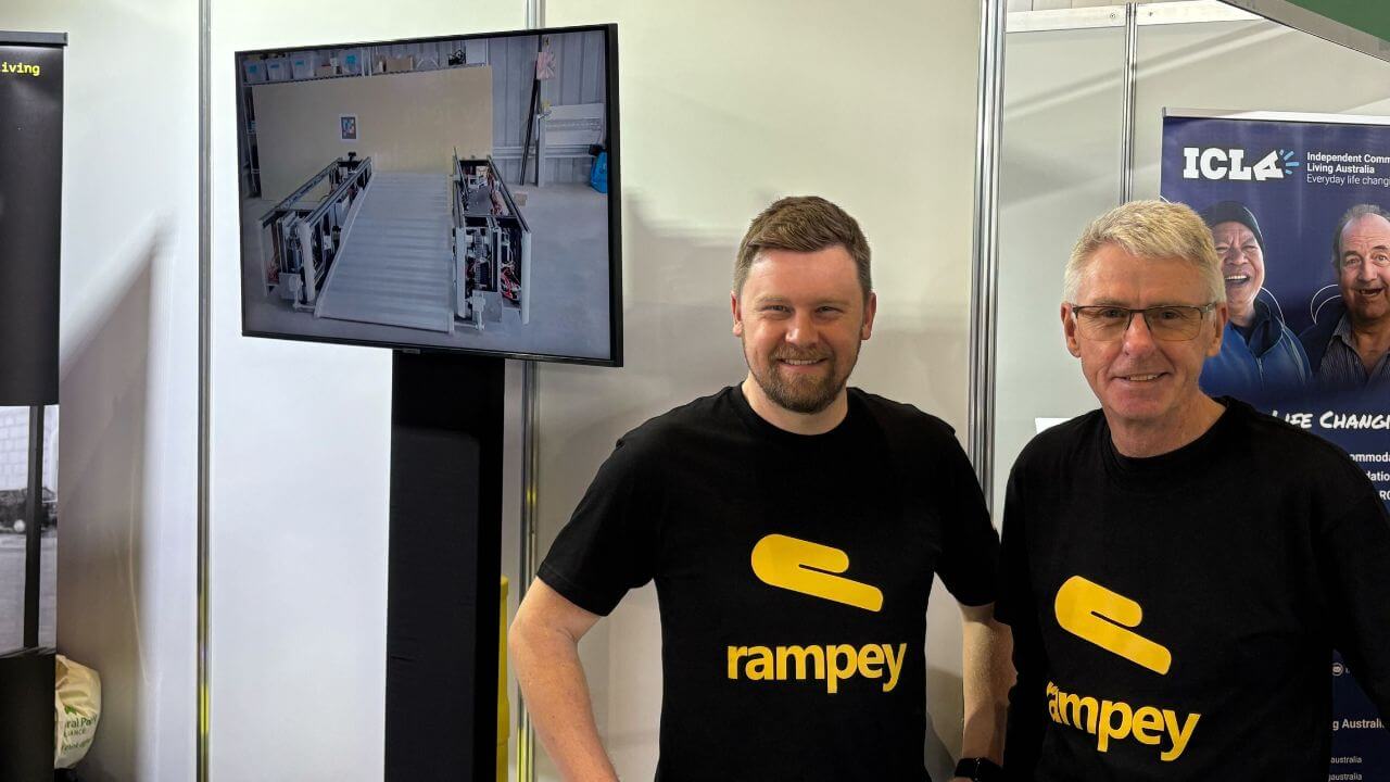 Rampey founder Jay Davey, with  Stewart Davey at the expo booth, showcasing Rampey's innovative technology with a train simulation and display screen.