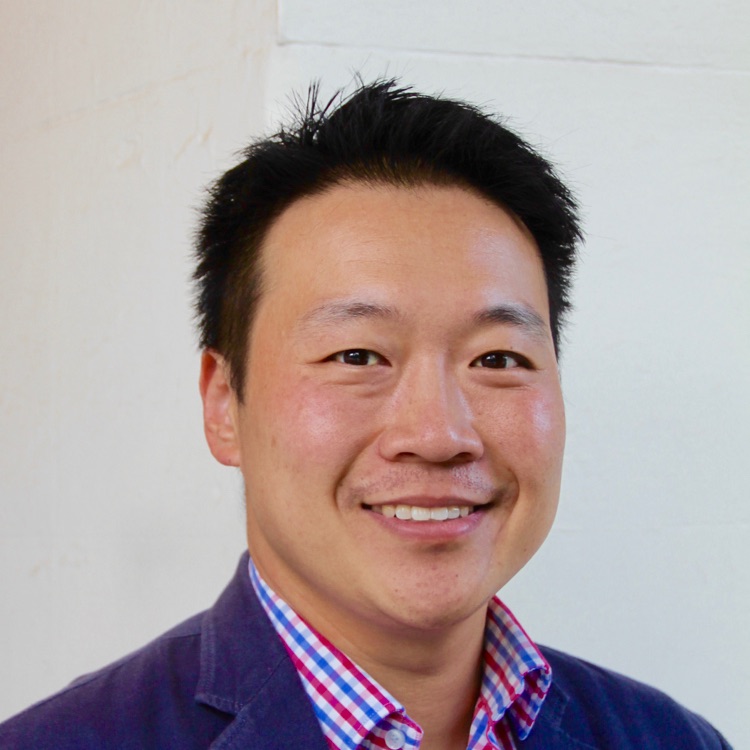 Asian male with short hair, wearing a blue suit and plain business shirt.