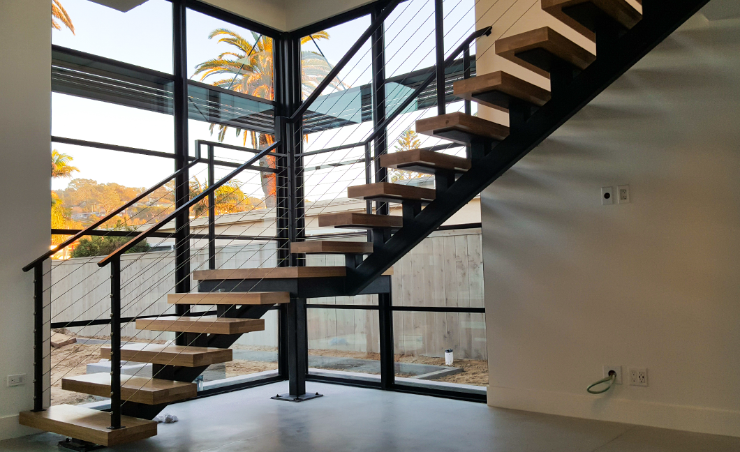 Floating steel stringer staircase with cable railing in a bright modern San Diego home