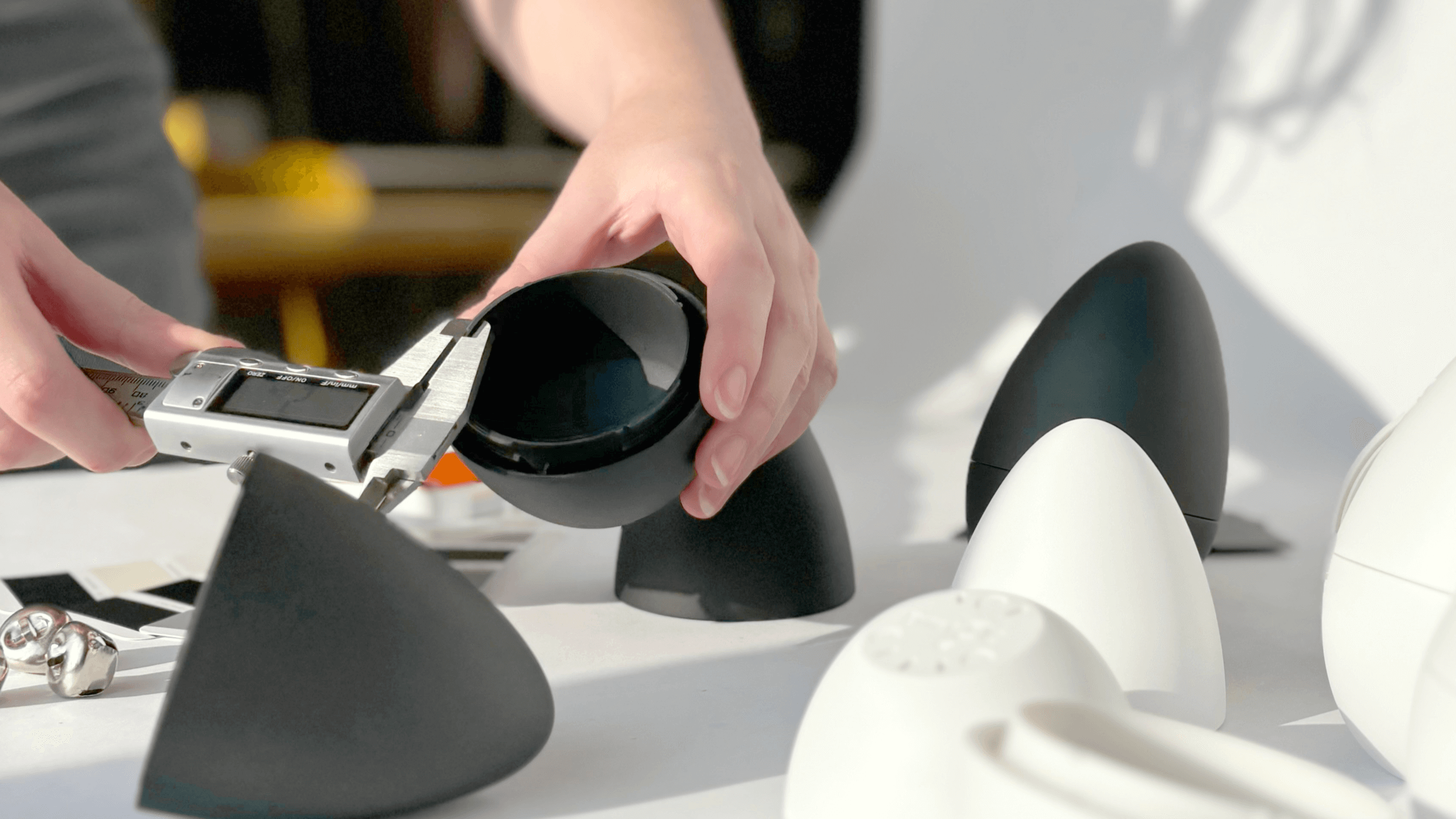 Industrial designer measuring EurekIA prototype components during precision product engineering and hardware development.