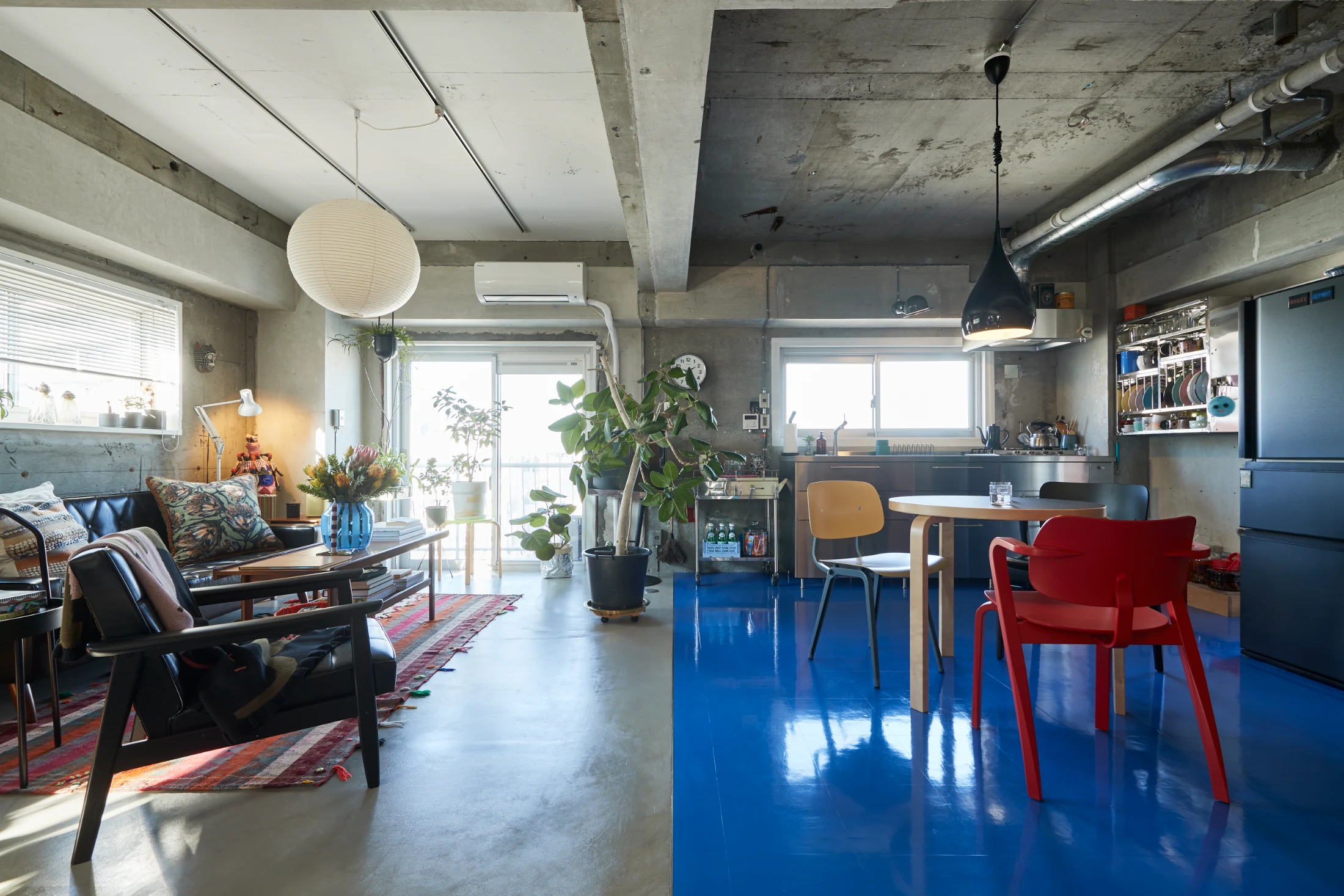 The split floor finishes of polished concrete and blue PVC tiles not only demarcate the living and kitchen areas but they also allude to the couple's contrasting tastes.