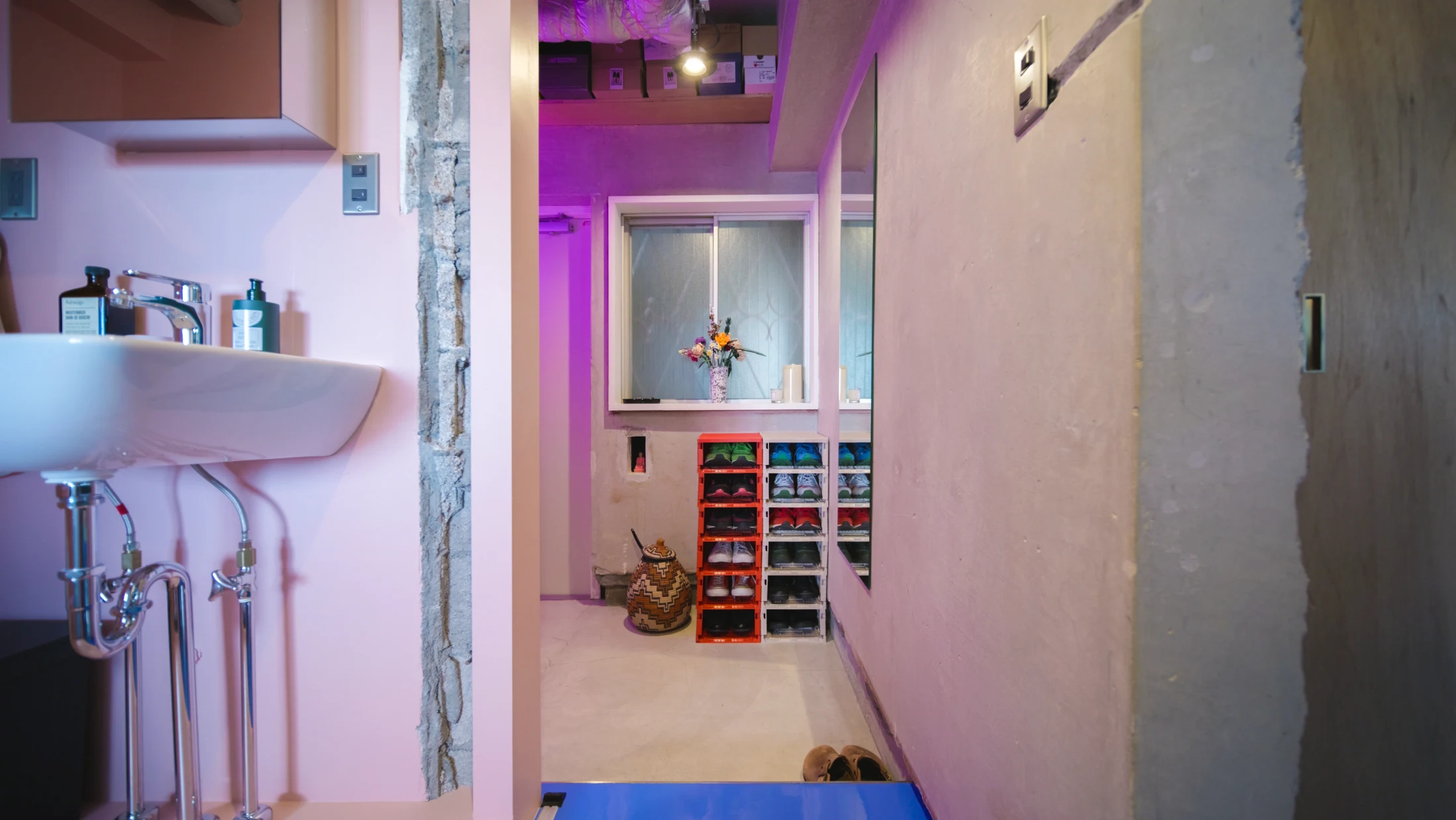 (ABOVE RIGHT) David and Koichi's contemporary take on a genkan – the entryway in Japanese homes that acts as the interface between the outside and inside domains – where shoes are removed and replaced with house shoes or slippers. David and Koichi's version is enhanced by space efficient and colourful shoe storage and a violet wash of light. Note, David and Koichi store shoe boxes containing more irregularly worn pairs of shoes in a high shelf above. Image: Never Too Small.
