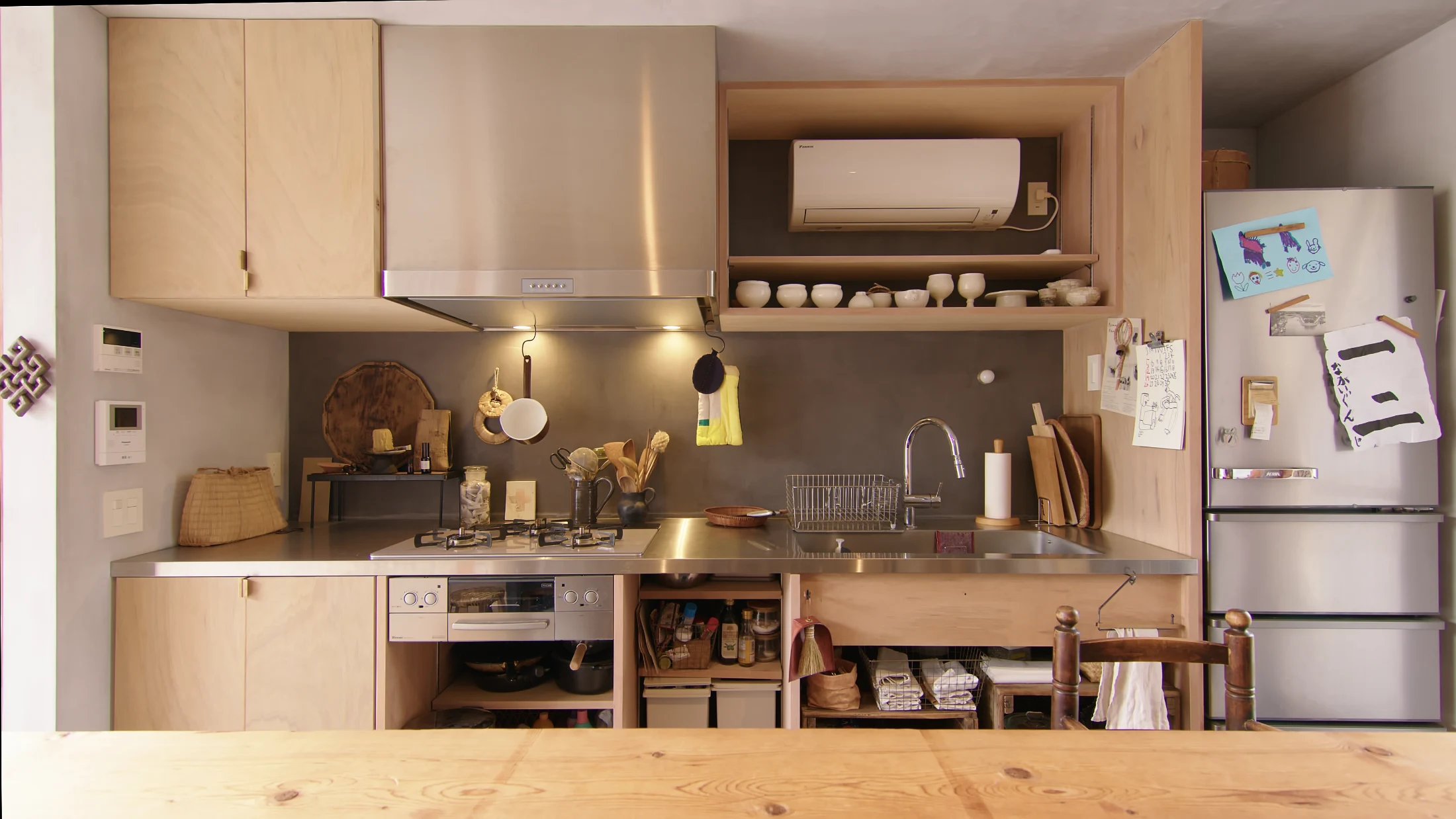 At House in Heguri in Kyoto, designed by Yousaku Tsutsumi of Arbol Design, functionality and organisation is prioritised in the kitchen without sacrificing character and charm. Handmade pottery and a woven basket house regularly used utensils and practical hooks keep other items within easy reach. Image: Never Too Small.