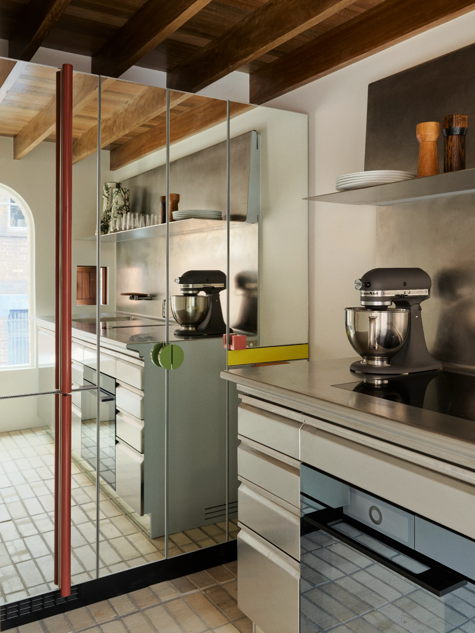 Full height cabinetry in the kitchen is clad in mirror to expand the the sense of space and reflect light from the facing window.