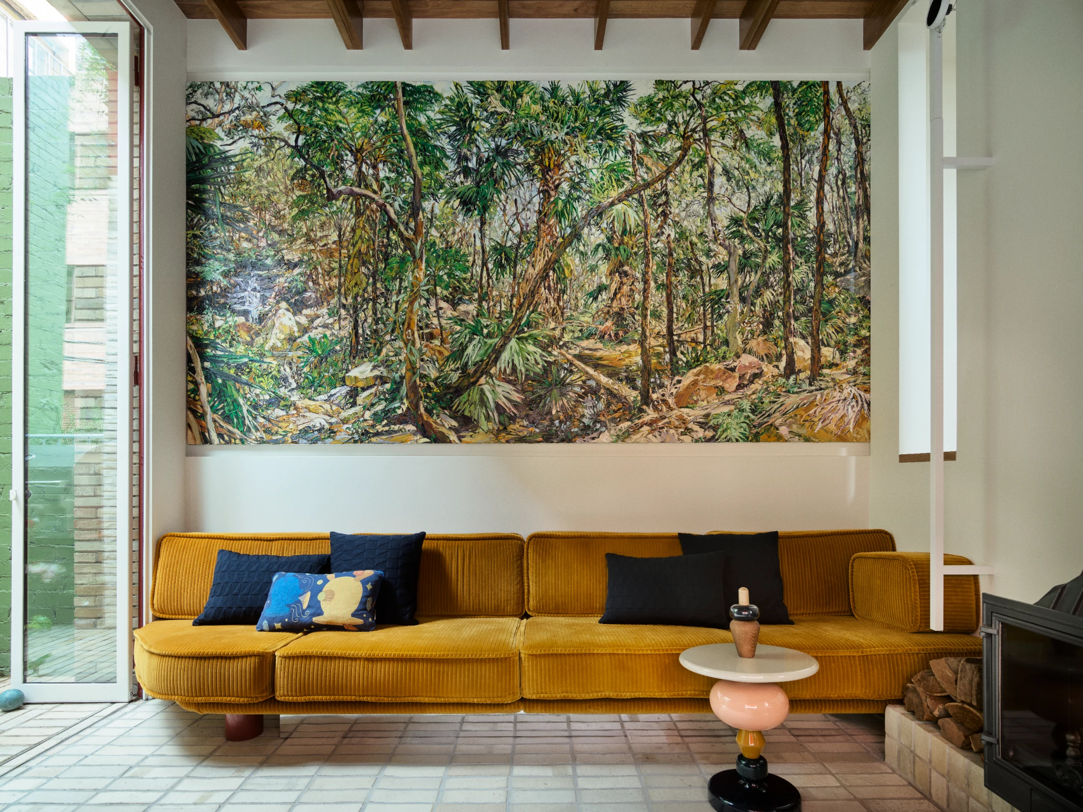 Eora by the late Nicholas Harding spans four metres above the custom sofa Adam had upholstered in gold corduroy to complement the painting.