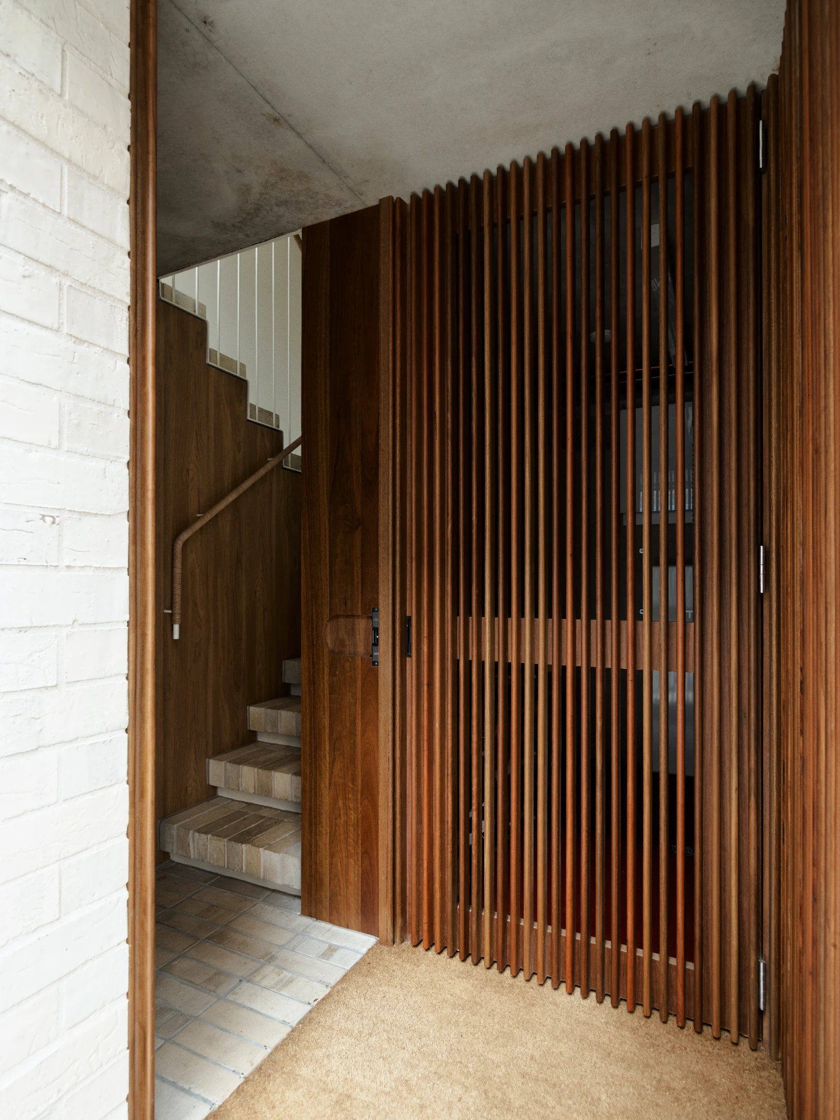 Storage and utilities are concealed by elegant timber slatted panels at the home's entrance.