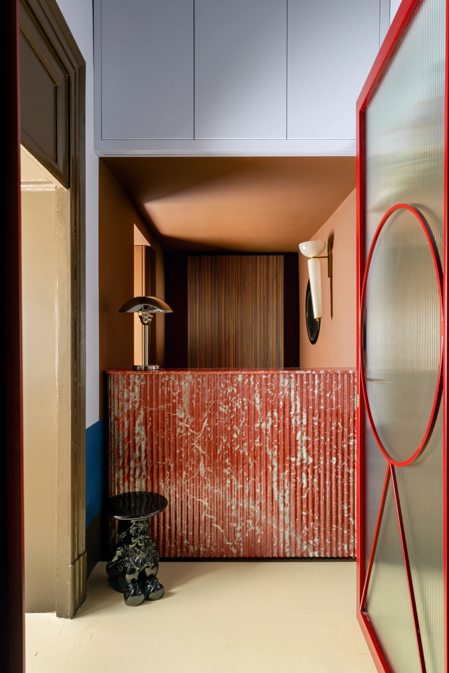 A more subdued palette of muted shades of blue, brown and red appear in the apartment's entrance area before increasing in intensity further into its other rooms.