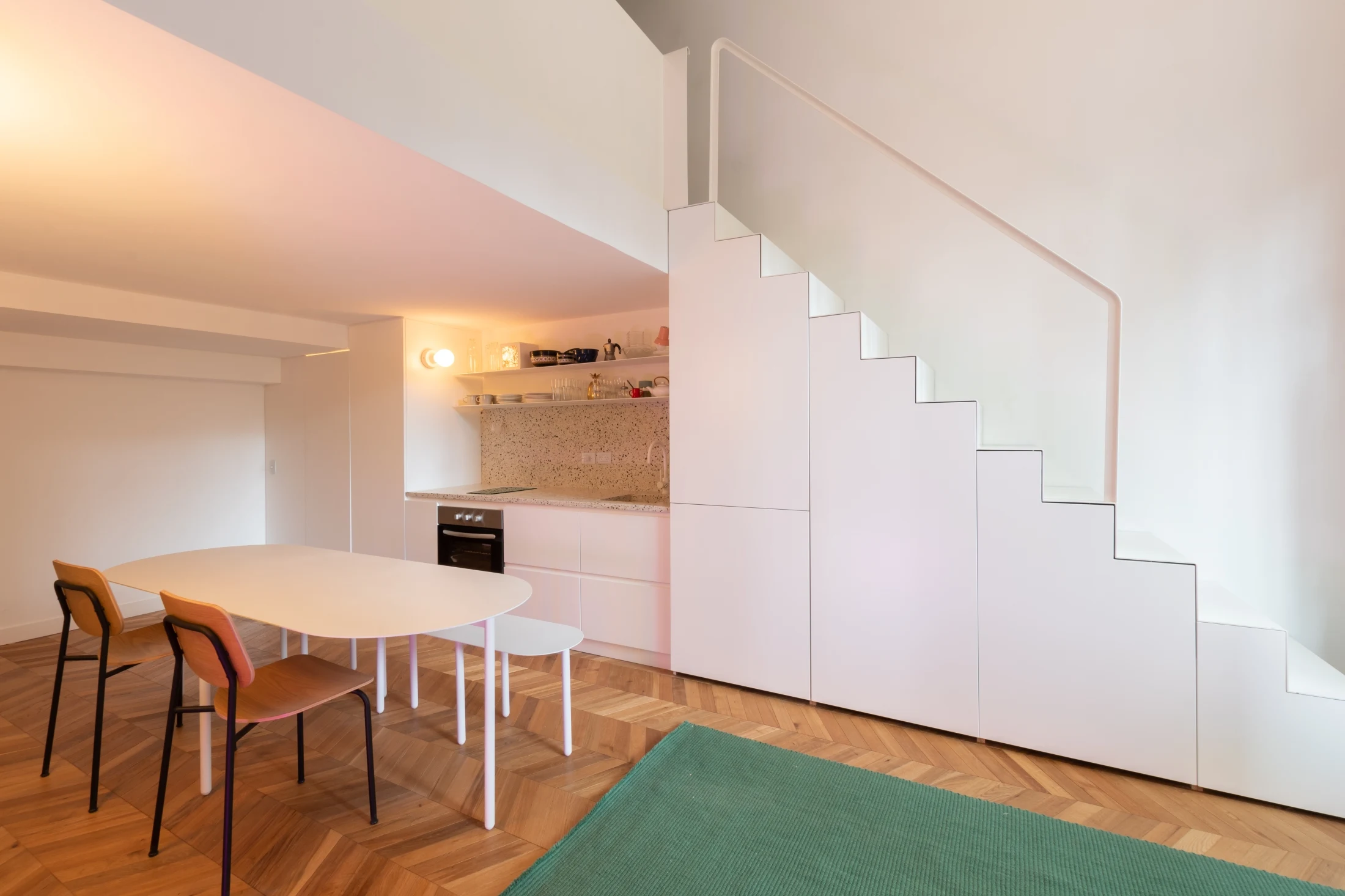 Seamless joinery is cleverly integrated into the staircase of Studio Seguí, providing space for a small fridge, pantry, and additional storage. The minimalist kitchen designed by Carol Burton also features a terrazzo counter and splashback, a double-burner