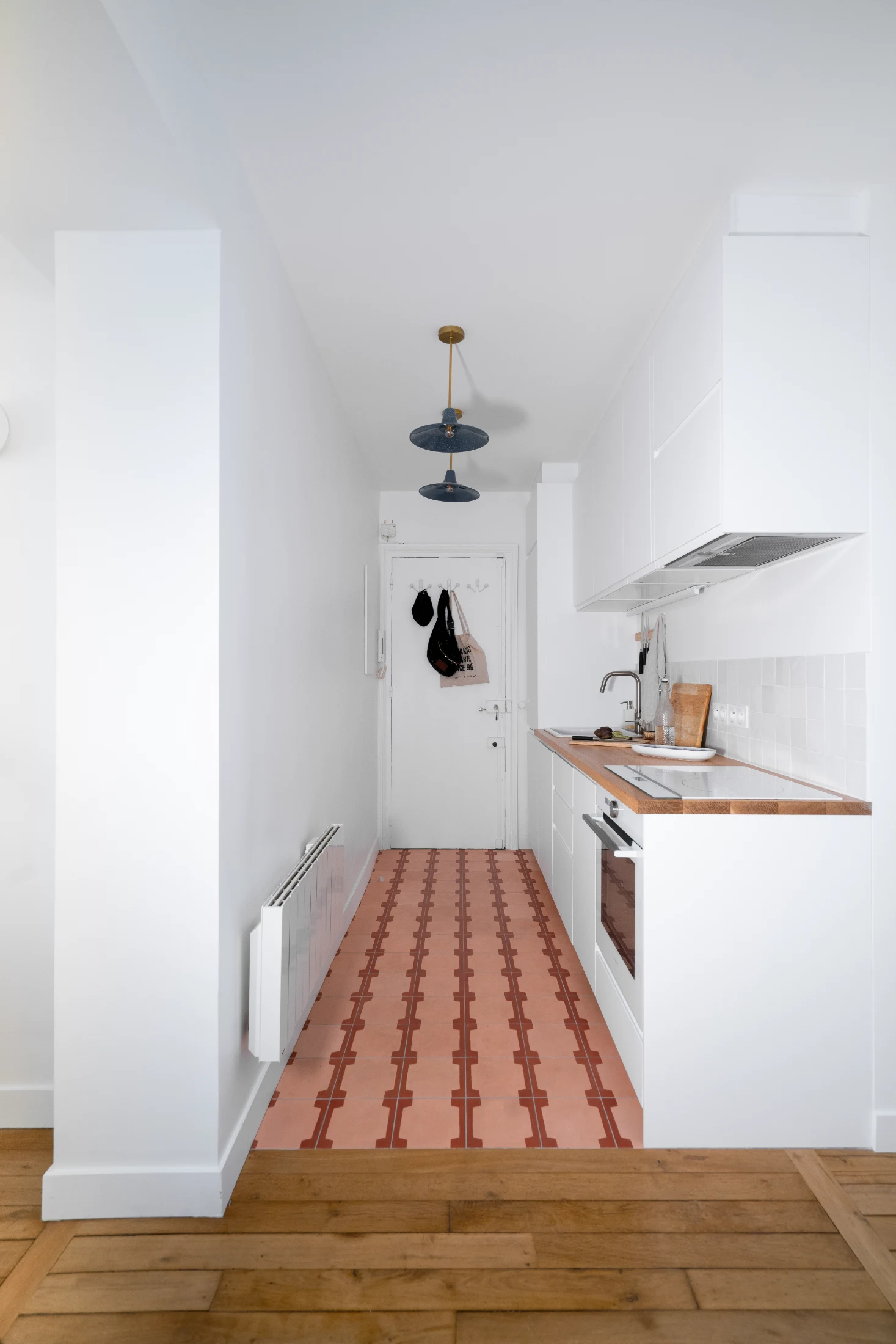 In The Renovation of Appartment un'D Jourdain designed by Meraki Architecture the kitchen occupies just one side of an entrance hall in an incredibly efficient use of space and storage. Elegant and thoughtful details such as contrasting flooring (in this c
