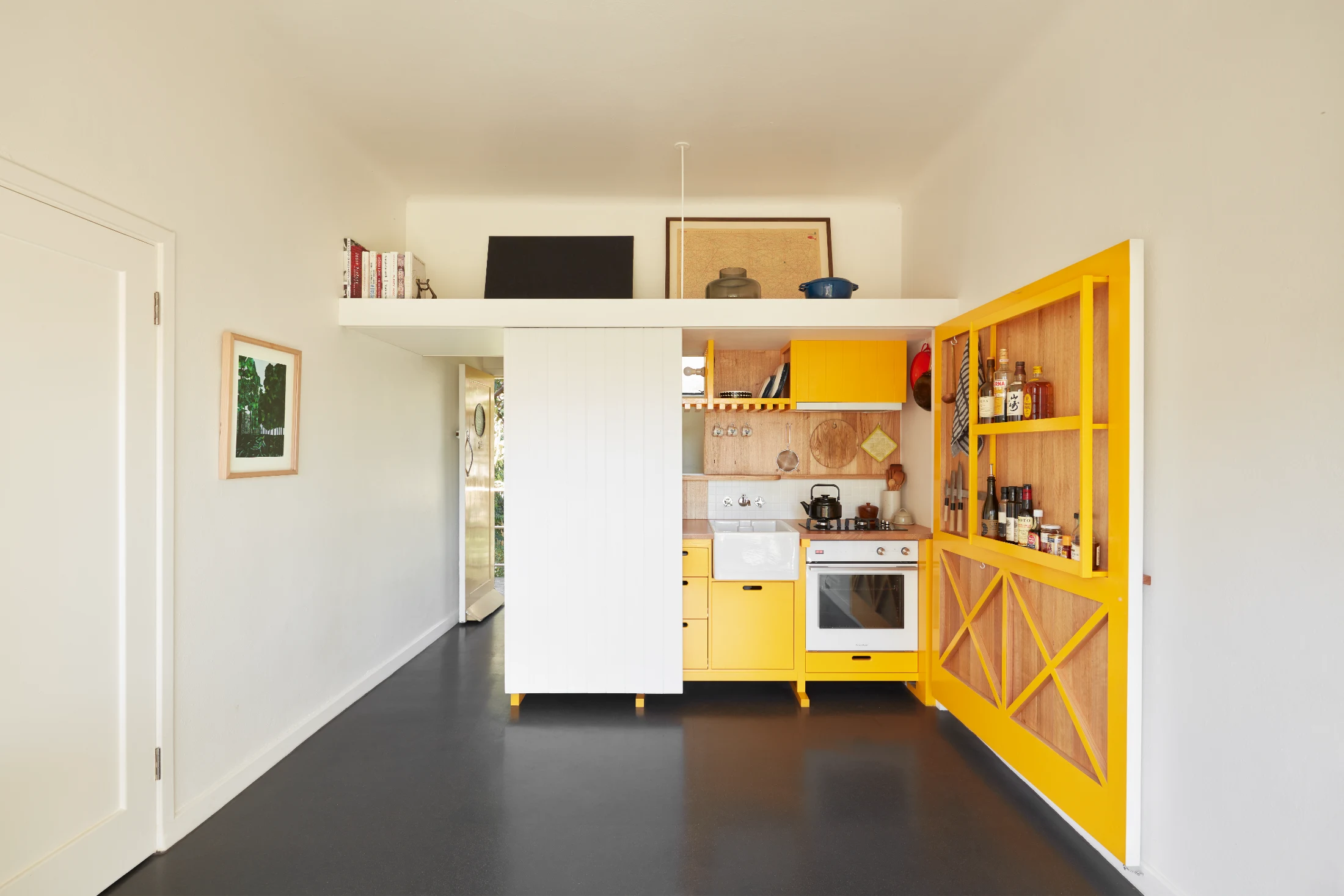 In the diminutive Cairo Apartment designed by Nicholas Agius of Agius all is not what it seems. Hidden behind what appears to be a large white cabinet is a cheerful yellow kitchen, which works its footprint even harder with pantry and other storage feature