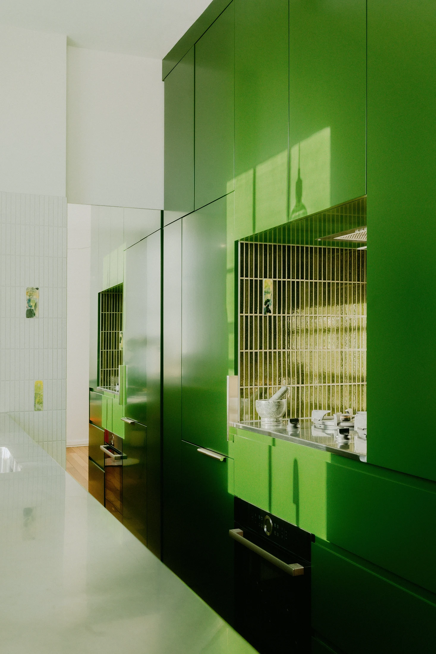 Eleanor Peres wanted to create a special feature in her kitchen mono studio so she commissioned a friend to design a series of custom ceramic inset tiles to scatter around the kitchen in between the green and white Japanese Kit-Kat tiles.