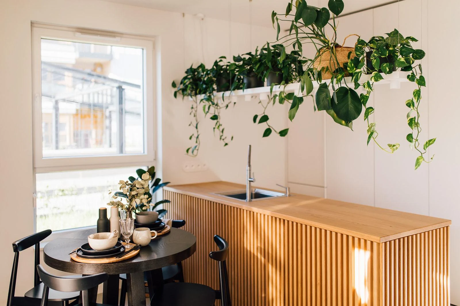 The suspended shelf that hangs above the kitchen island in Alicja Szmal-Baehr's Projekt Własny is not only for plants but also elegantly houses task lighting for the island.