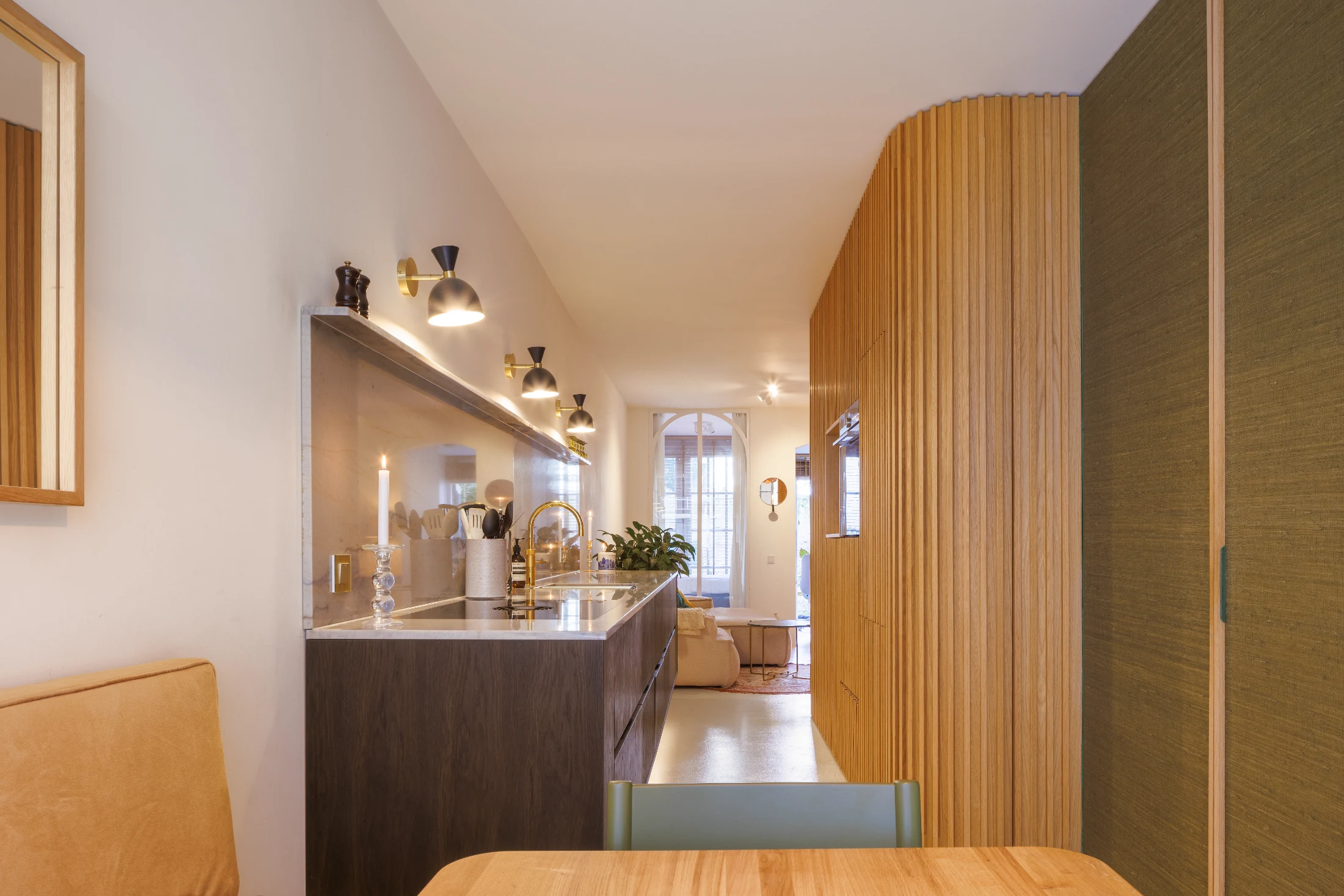 In Project Jordaan designed by MI Studio, gold-trimmed wall lights provide both task and ambient lighting, while under-cabinet illumination gives the kitchen a striking floating effect.