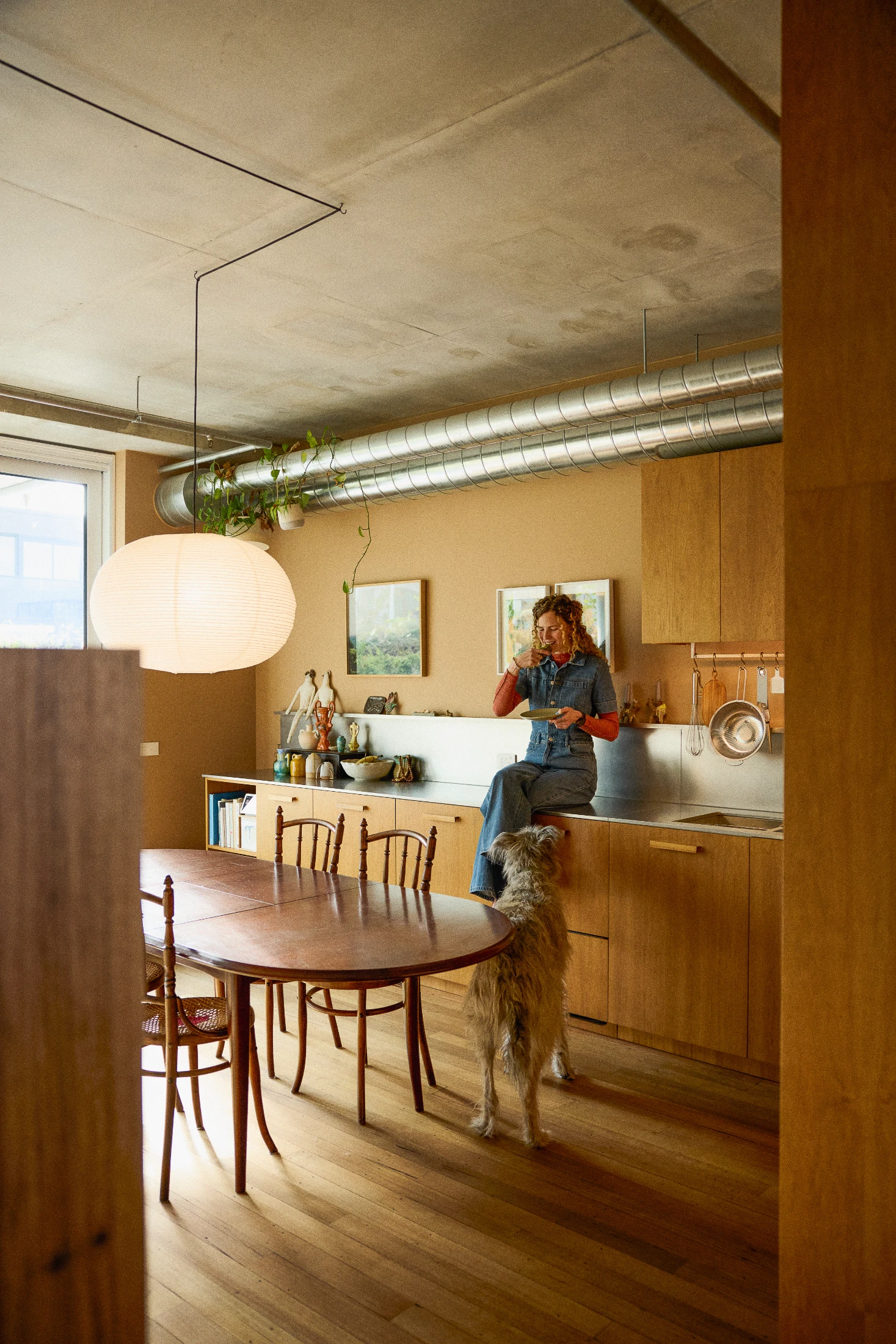 Maddie perched on her kitchen bench which has a gentle luminosity yet forgiving robustness on account of the 'orbital' finish she specified for the stainless steel.
