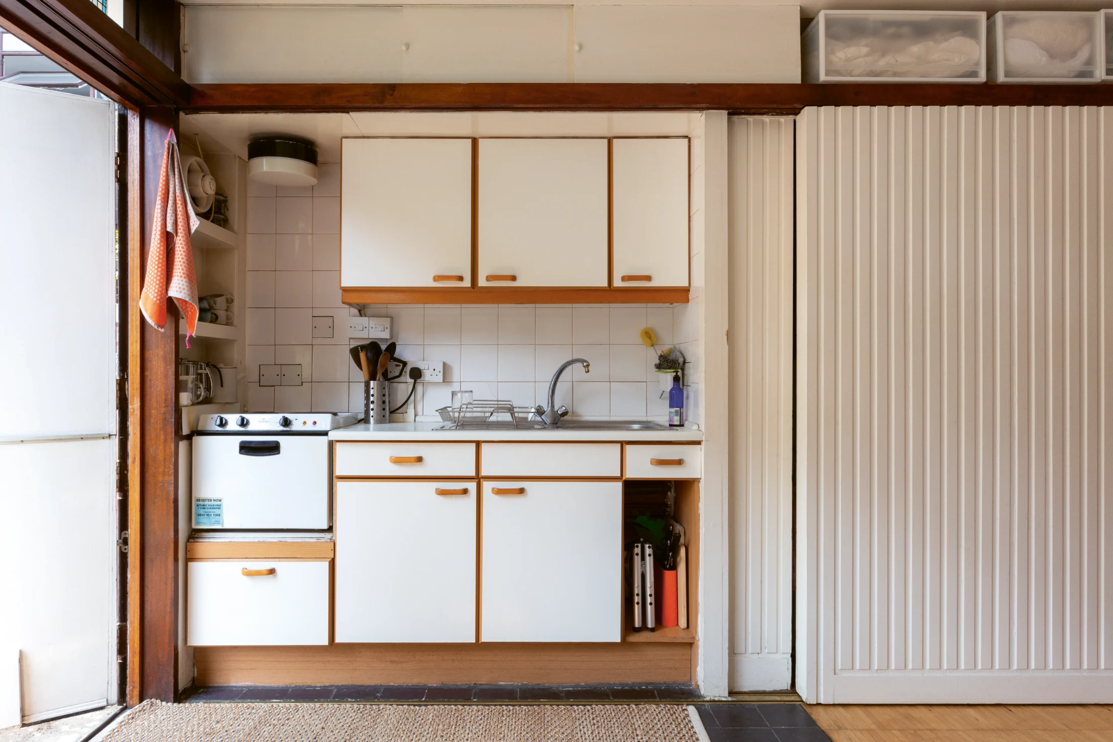 A one-room garden flat in Hatfield House within Golden Lane Estate with its floor divided in two by quarry tiles and finger parquet. Space for a single bed was allowed for in a recess to the right of the kitchen and both kitchen and bedroom could be concea