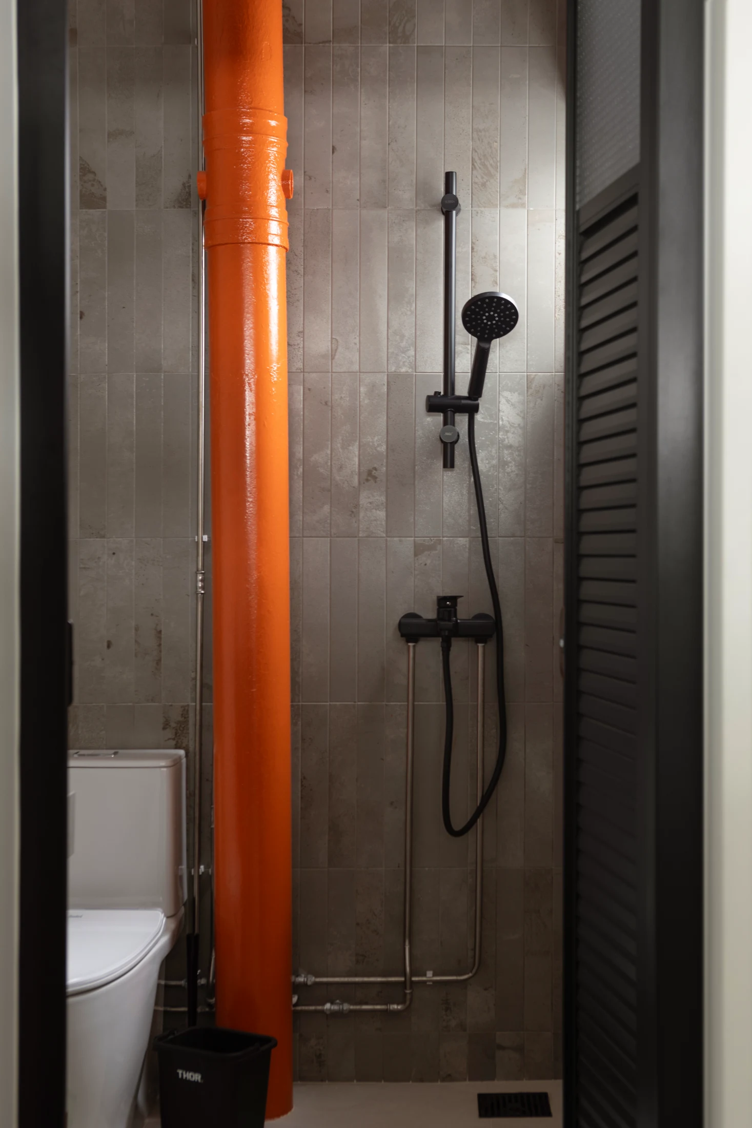 Rather than boxing in a large pipe and making the bathroom smaller, a lick of orange paint makes a feature of it.