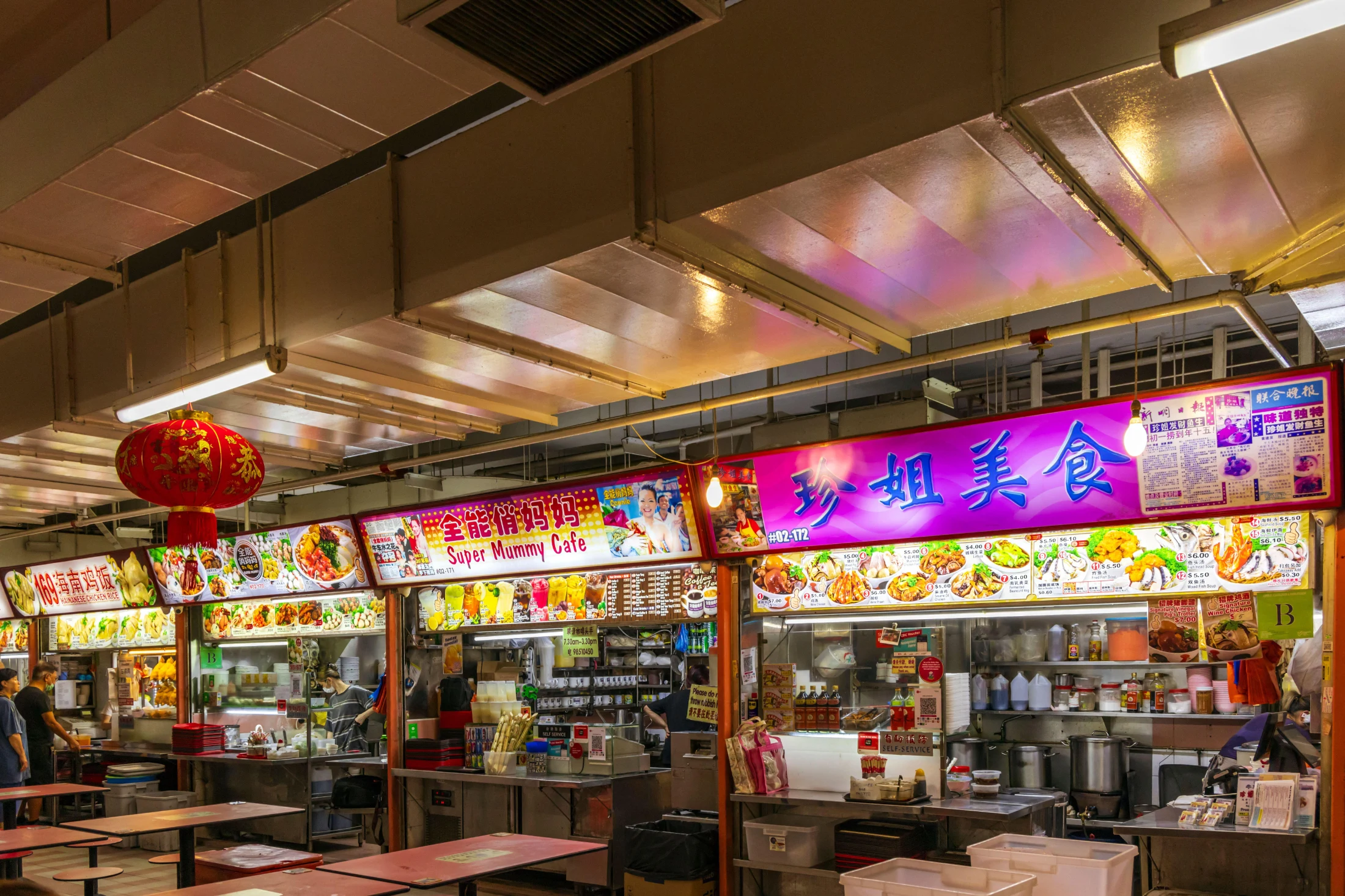 The bright and enticing stall fronts and signage of traditional Asian hawker stands in a Chinatown Hawker Centre. Image: Jim Monk / Alamy.