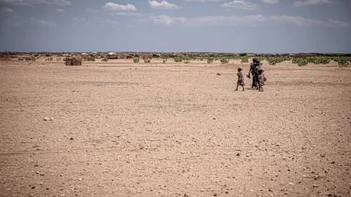 A woman and child walking in the desert.