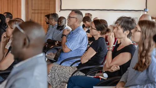 A group of people attentively listening to a speaker while sitting in chairs