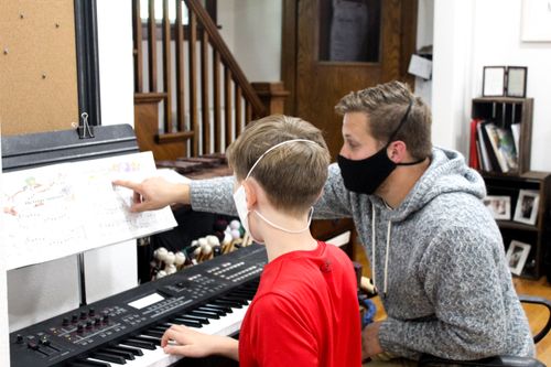 A teacher explaining his student how to play piano