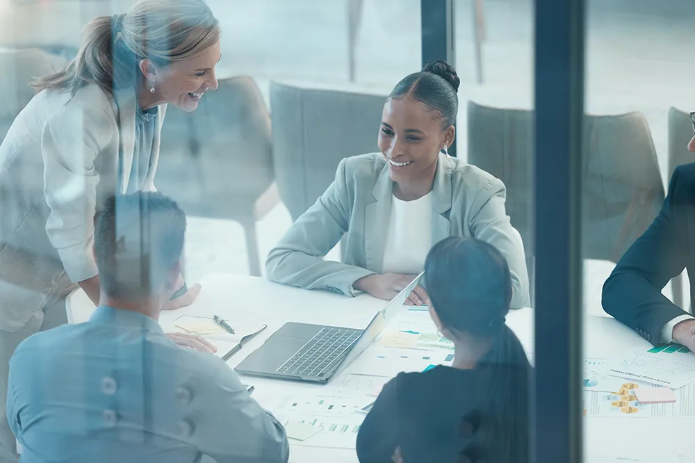 Group of diverse businesspeople having a meeting around a table with a laptop and documents.