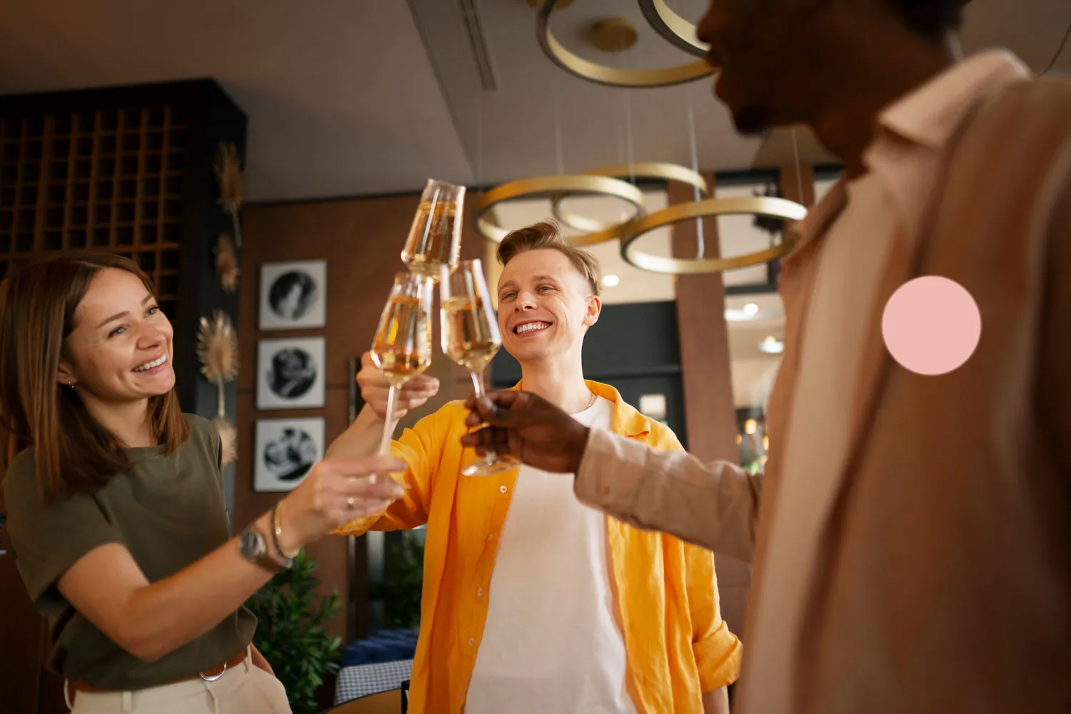 Three people working on computers in a modern office with large windows and exposed ceiling pipes.