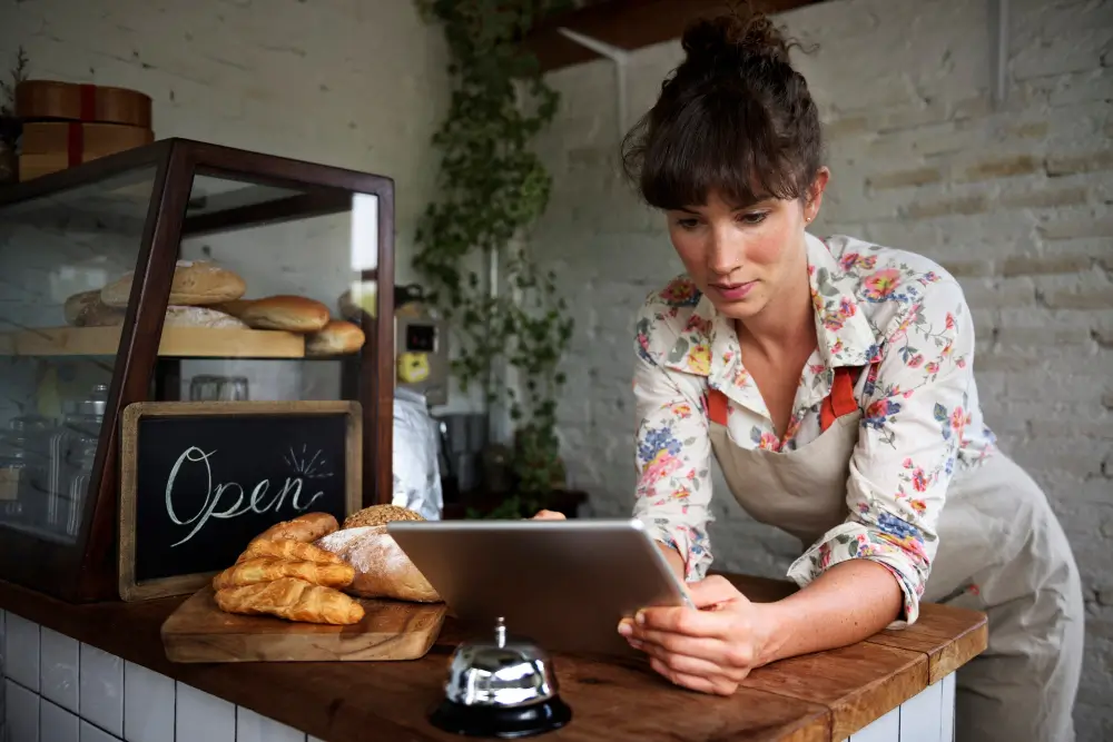 Two professionals sitting at a conference table engaged in discussion, with a laptop and coffee mug in front of them.