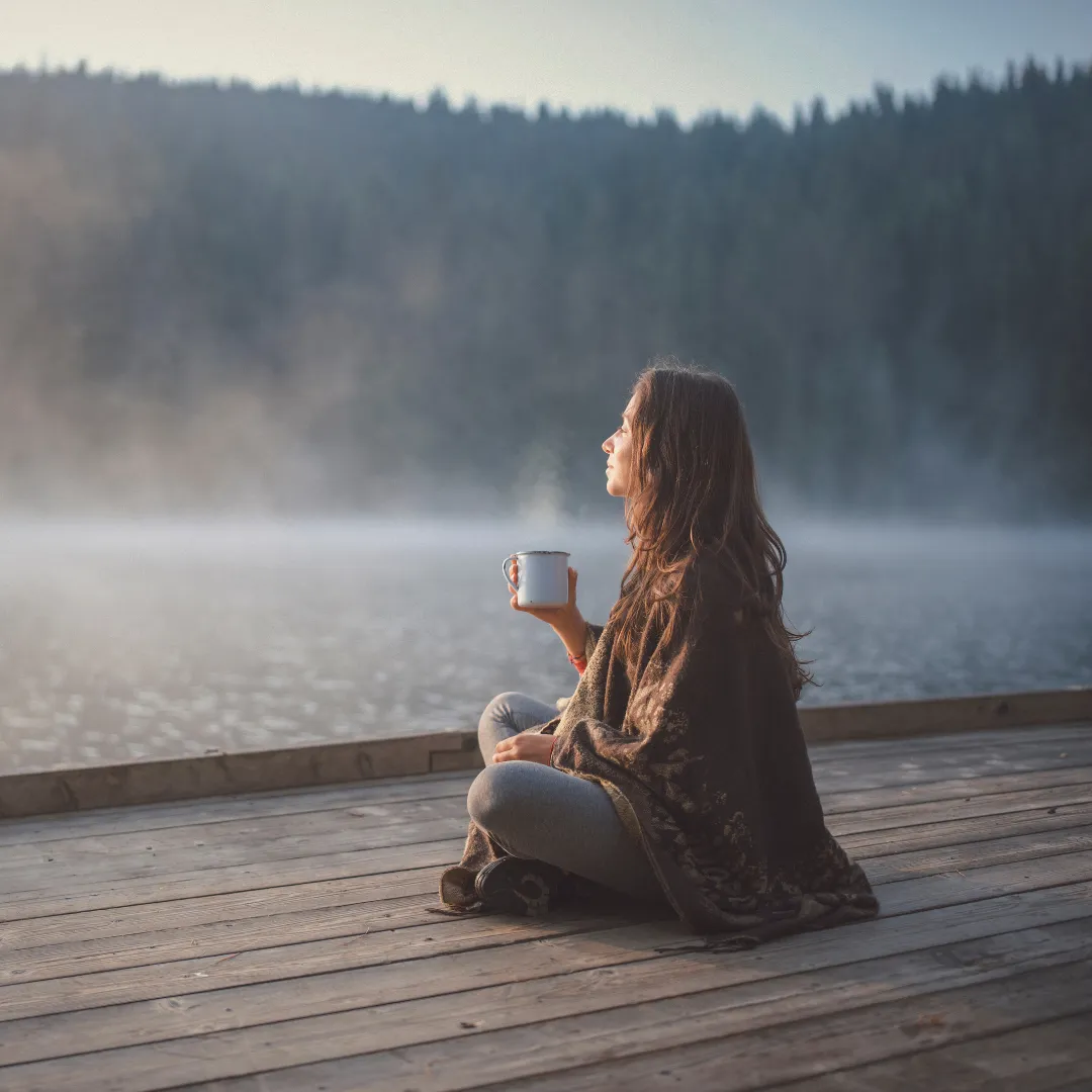 Woman Sipping Hot Drink On Lakeside Dock