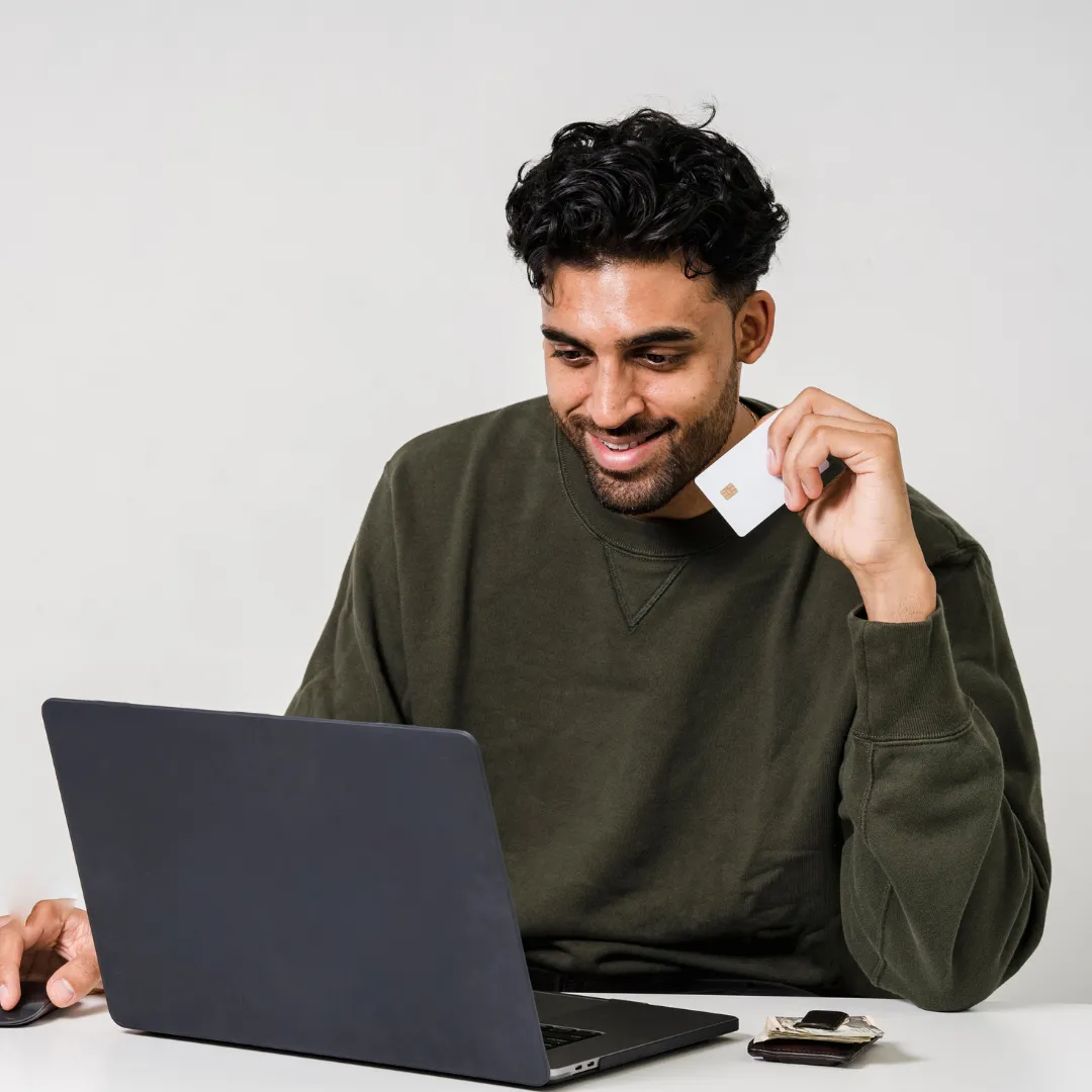 Man holding credit card and looking at laptop
