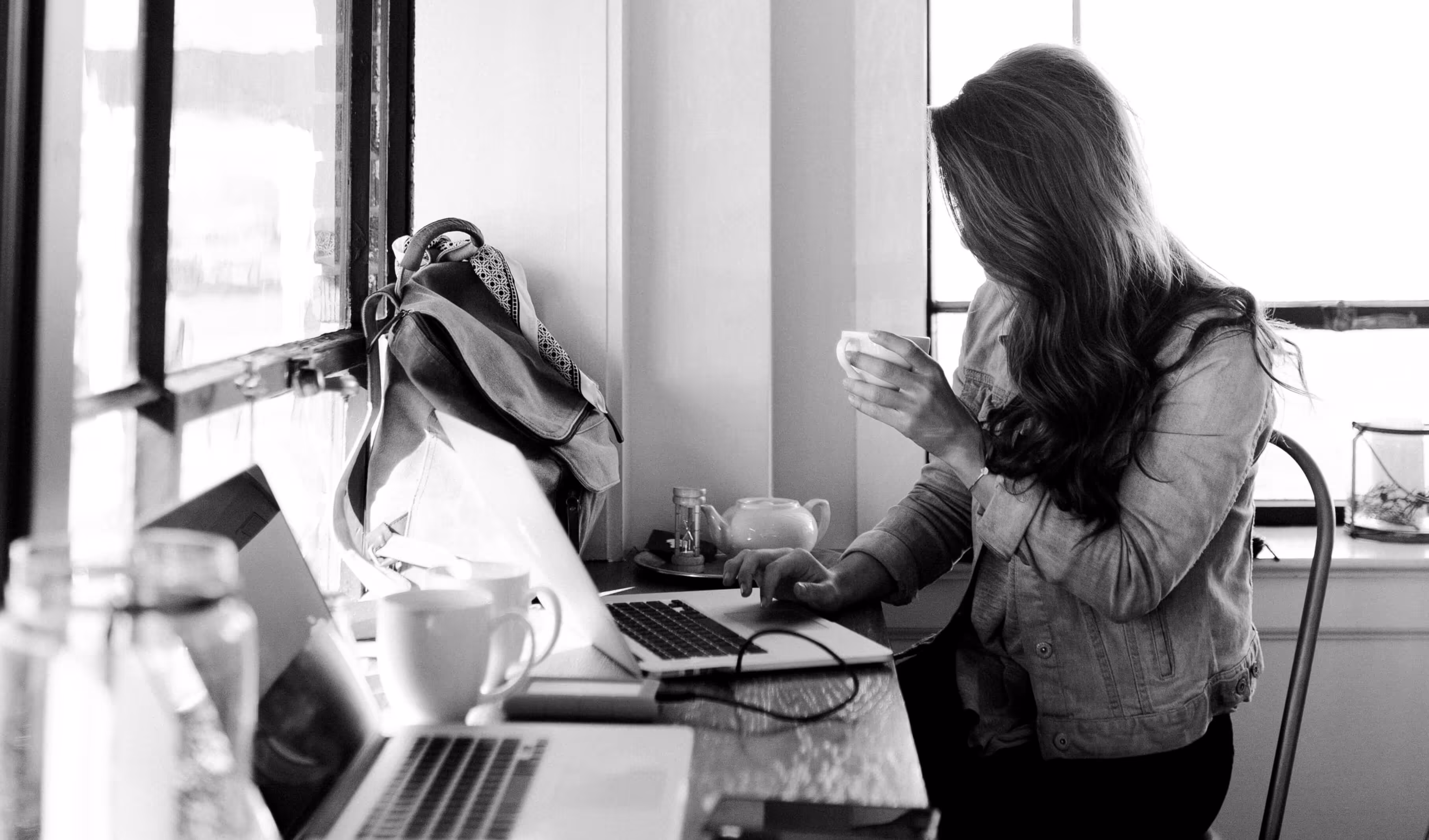 Black and white photo of a woman working on her laptop in a café