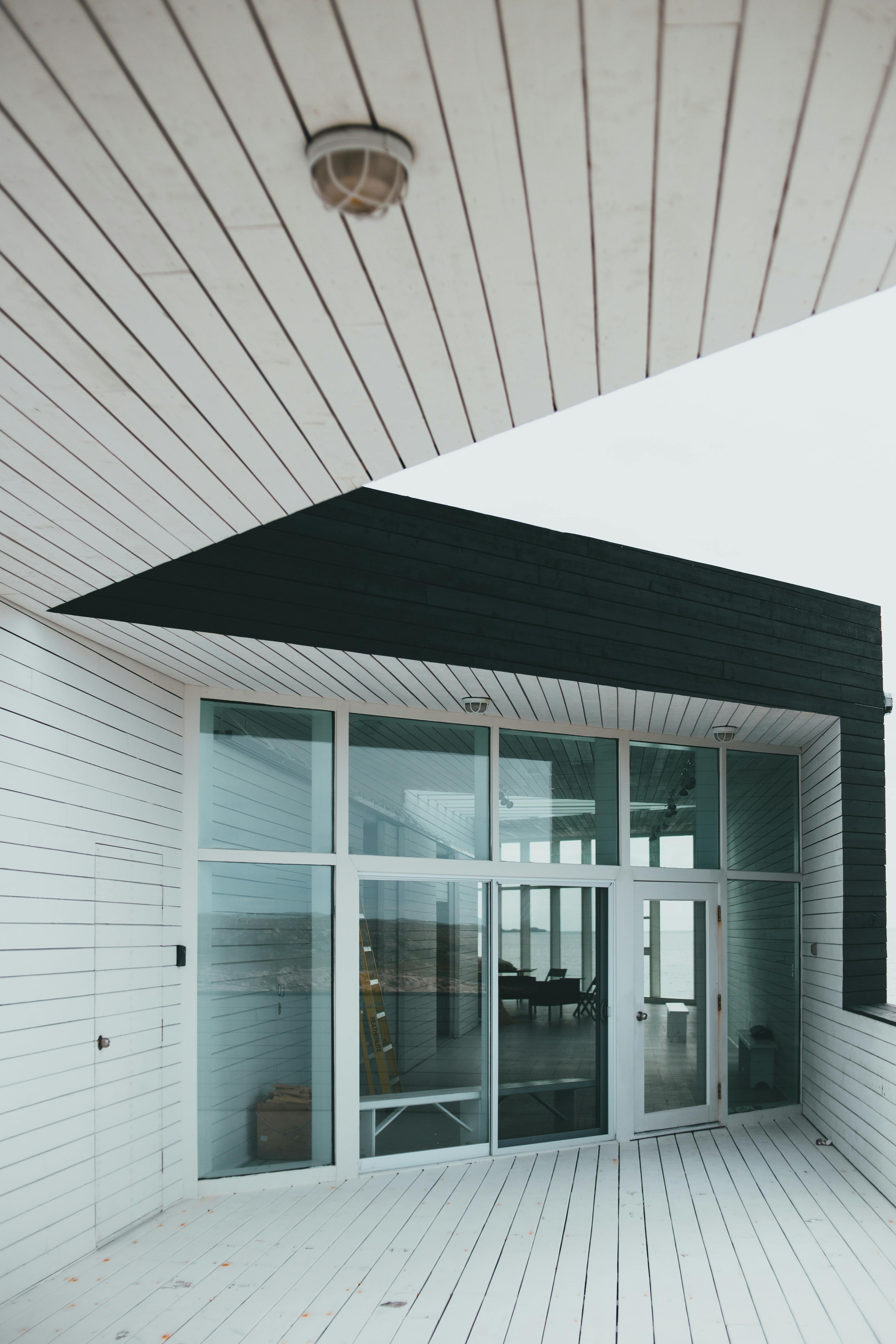 Coastal home exterior with large glazing and deep roof overhang providing passive shading. Credit: Photo by Erik Mclean: https://www.pexels.com/photo/a-white-and-black-building-8266719/