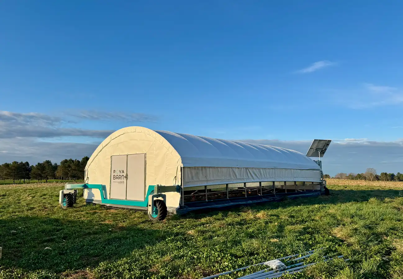 The ROVA|BARN 700 situated in an open pasture with solar panel extended, under a bright blue sky.