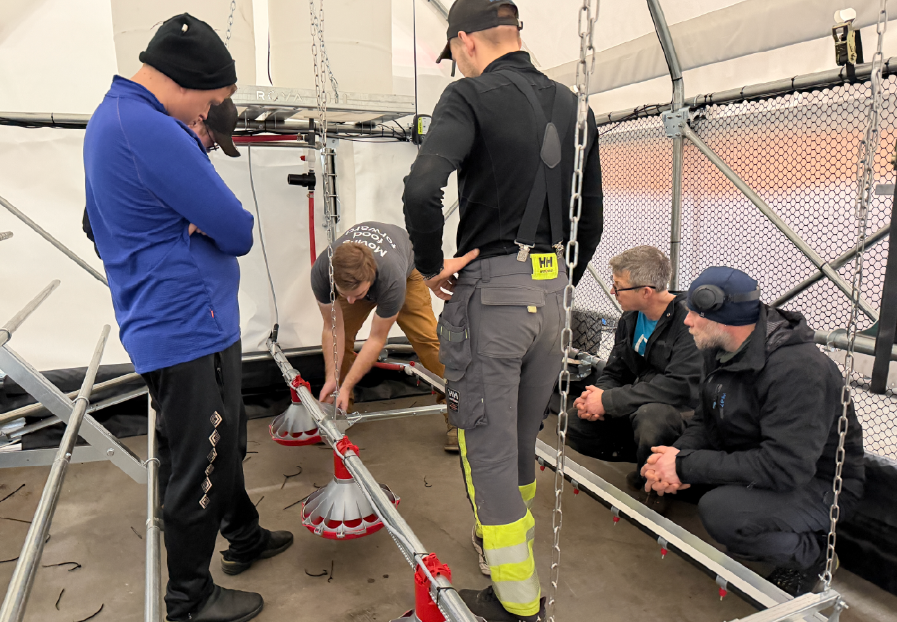 Farmers and technicians reviewing feed and water systems inside a ROVA|BARN during hands-on training session