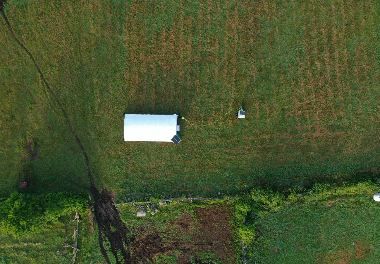 Mobile chicken coop moving across fresh pasture with pasture-raised chickens foraging on new grass.