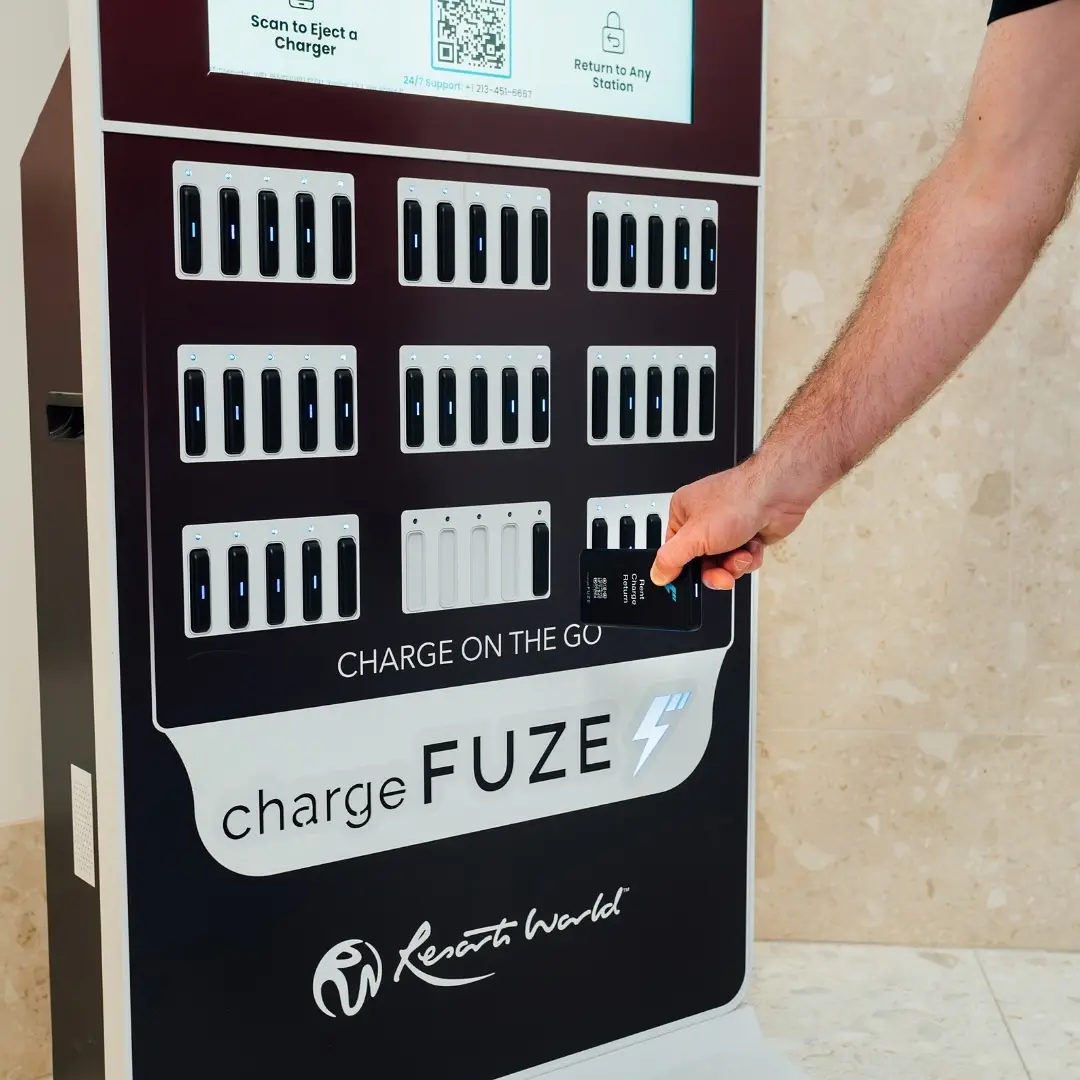 Wireless phone charging station by ChargeFUZE at Resorts World as a man returns a portable charger to the dark branded kiosk