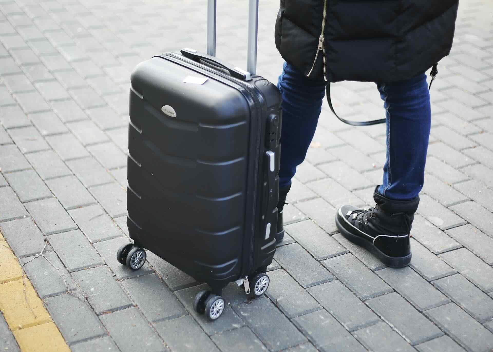 Person standing with black carry-on luggage