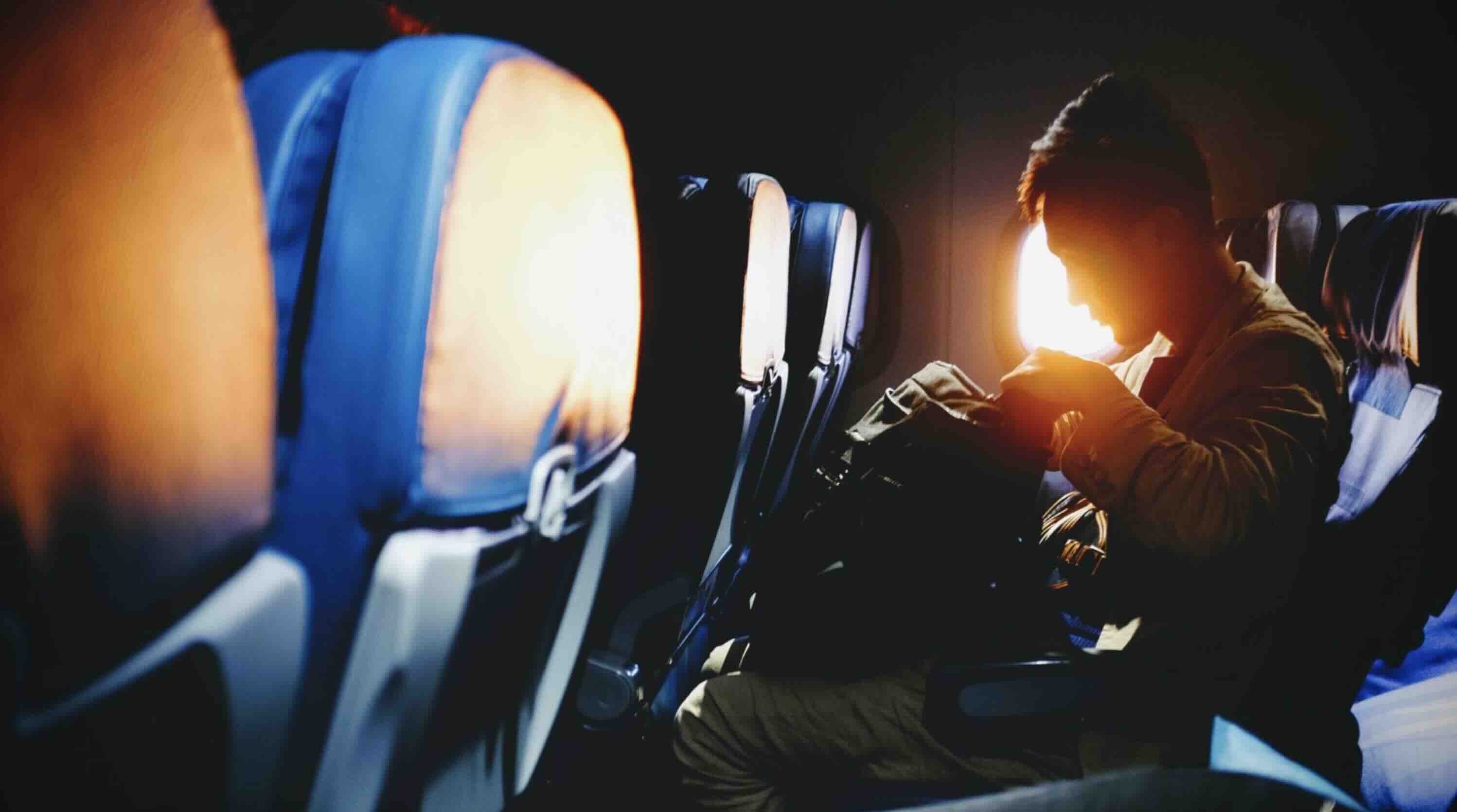 Man in his airplane seat with his backpack on his lap