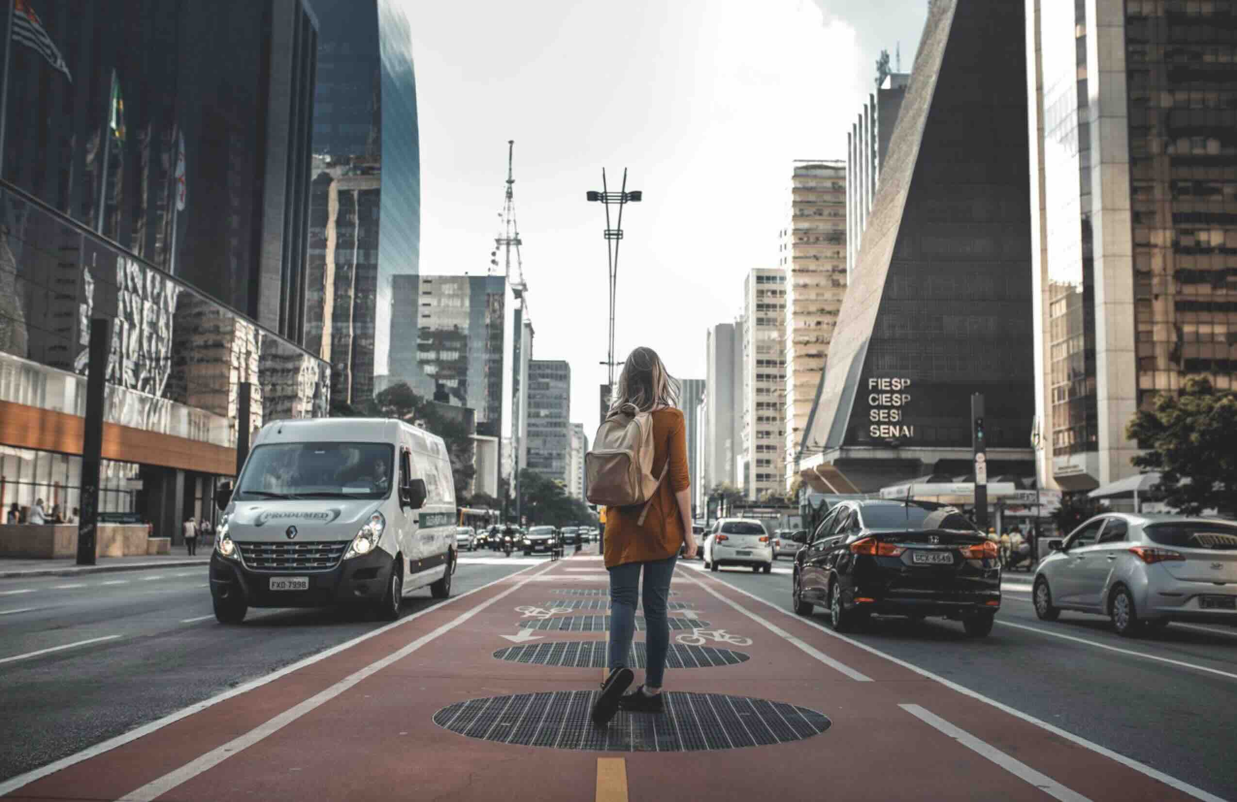 A young woman carrying a backpack and walking through a city
