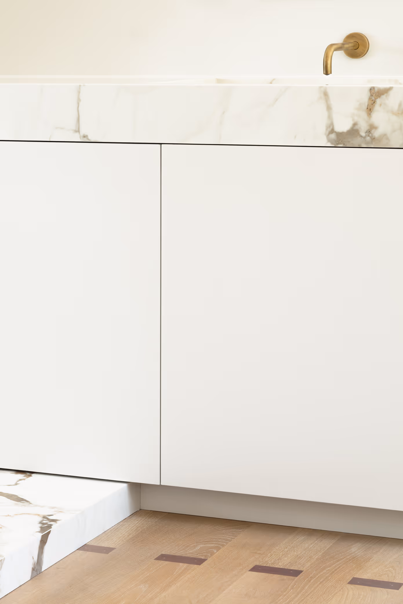 Detailopname van een witte marmeren wastafel met gouden kraan in een luxe badkamer