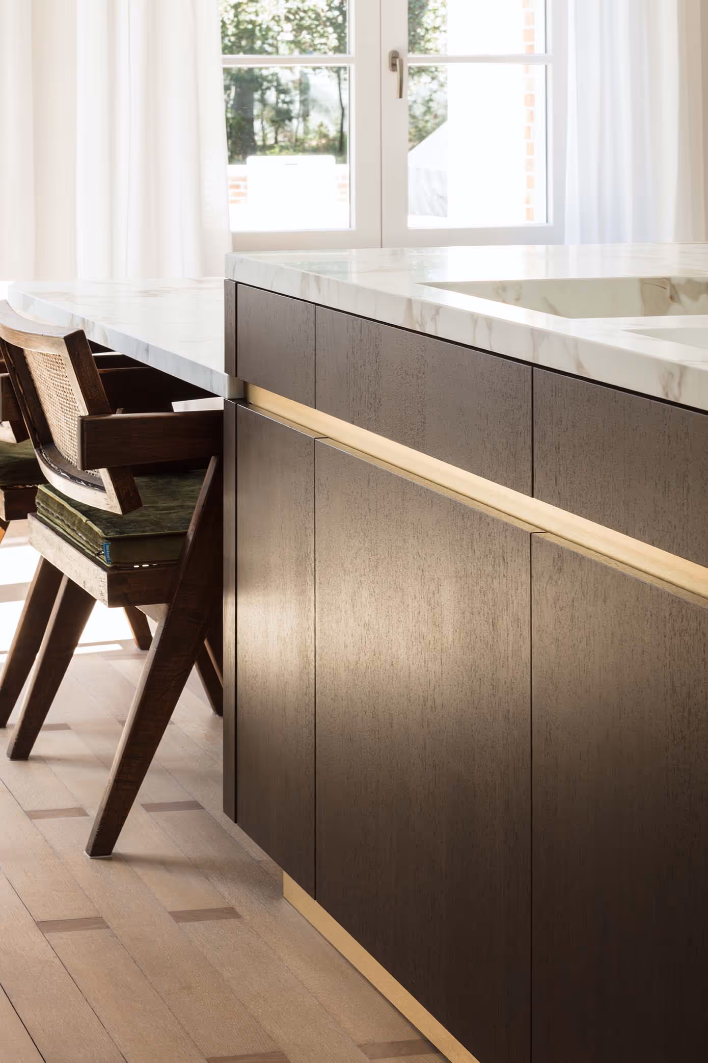 Detail van een donker houten keukenblok met marmeren blad en een geopende lade met groene stoffen