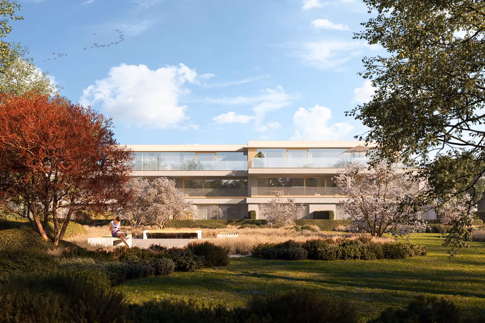Ruime tuin voor een modern appartementencomplex met een persoon zittend op een bankje genietend van het zonnige weer.