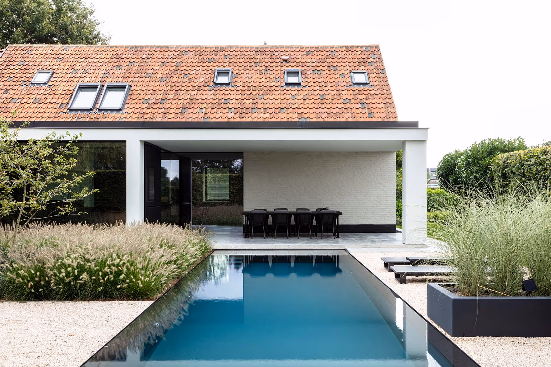 Elegant geïntegreerde buiten eetruimte en zwembad naast een huis met een traditioneel dak en moderne uitbouw