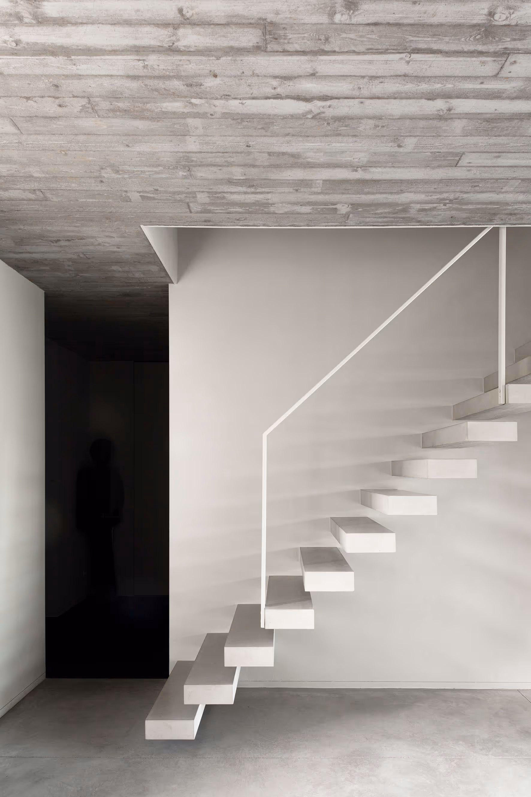 Minimalistische zwevende trap in een hedendaags huis met betonnen details.