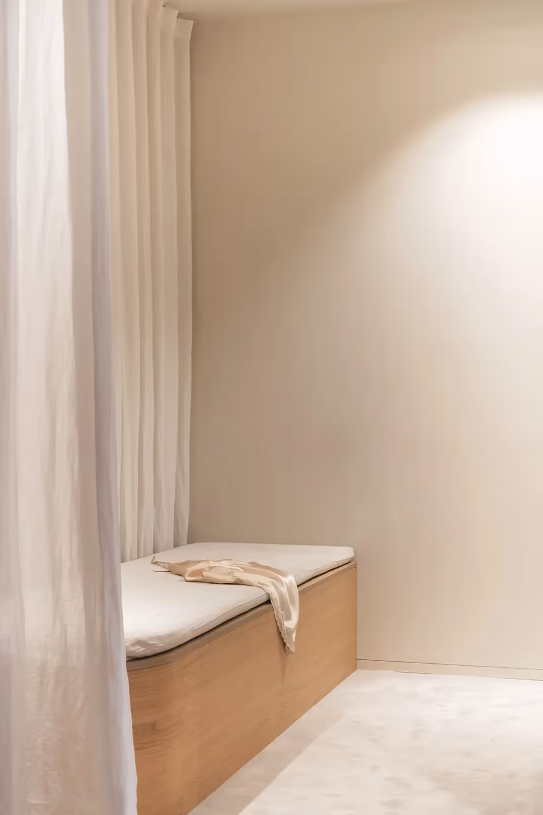 Minimalistisch interieur met een rustige zitbank en lichte, luchtige gordijnen.