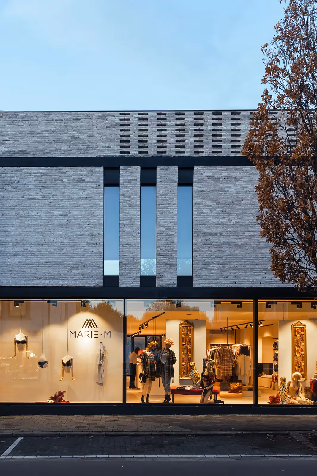 Close-up van een modern gebouw met een baksteenmotief en een groot glazen element.