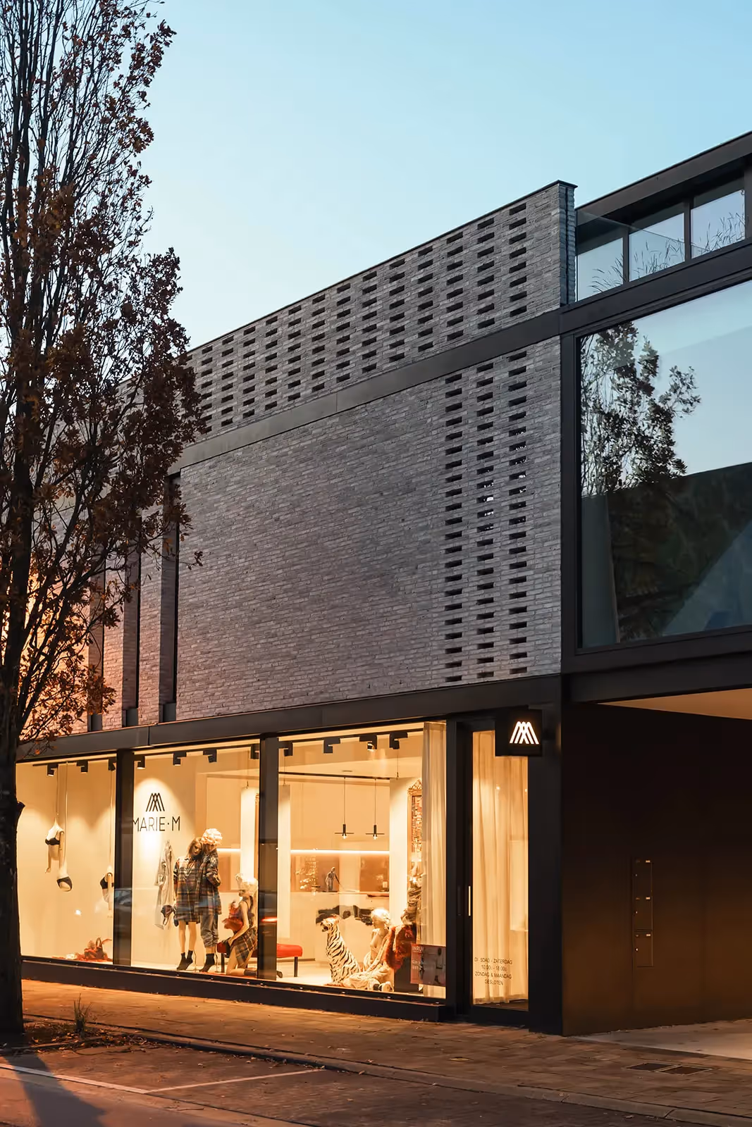 Close-up van een modern gebouw met een baksteenmotief en een groot glazen element.