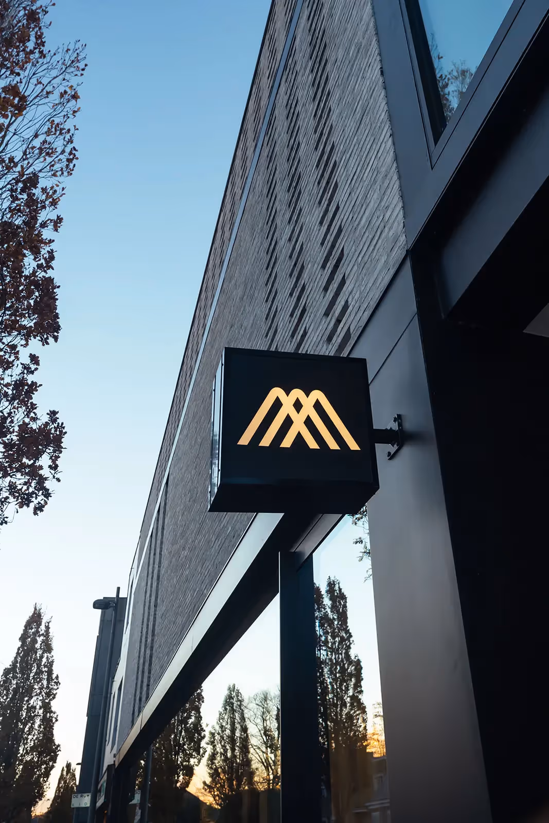 Stijlvolle zwarte buitenlamp tegen een moderne bakstenen gevel in de avondschemering.