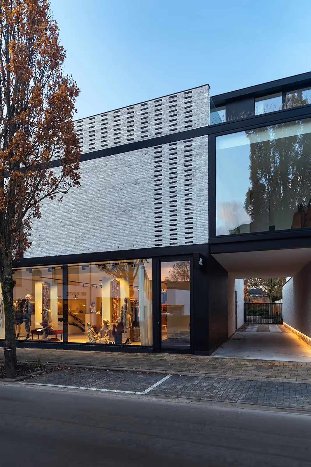 Close-up van een modern gebouw met een baksteenmotief en een groot glazen element.