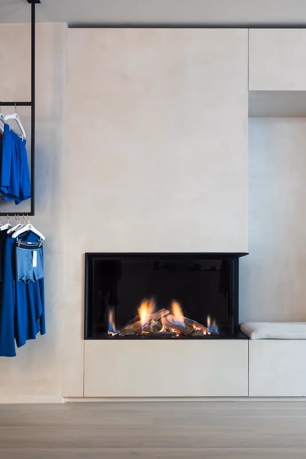 Interieur van een modieuze boetiek met ingebouwde gashaard en blauwe kleding op display.